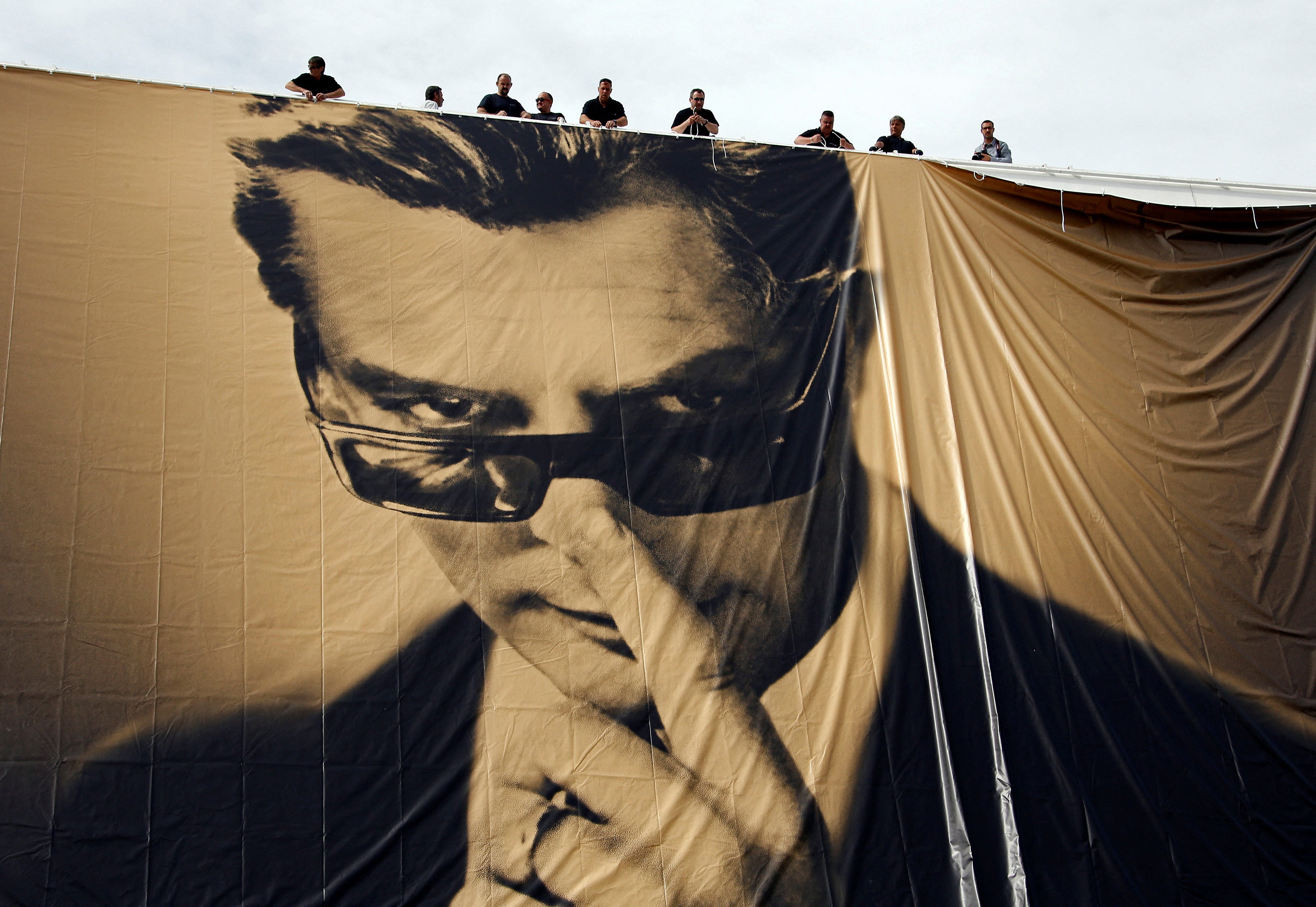 Workers set up a giant canvas of the official poster of the 67th Cannes, featuring late actor Marcello Mastroianni on the Festival Palace on 12 May 2014