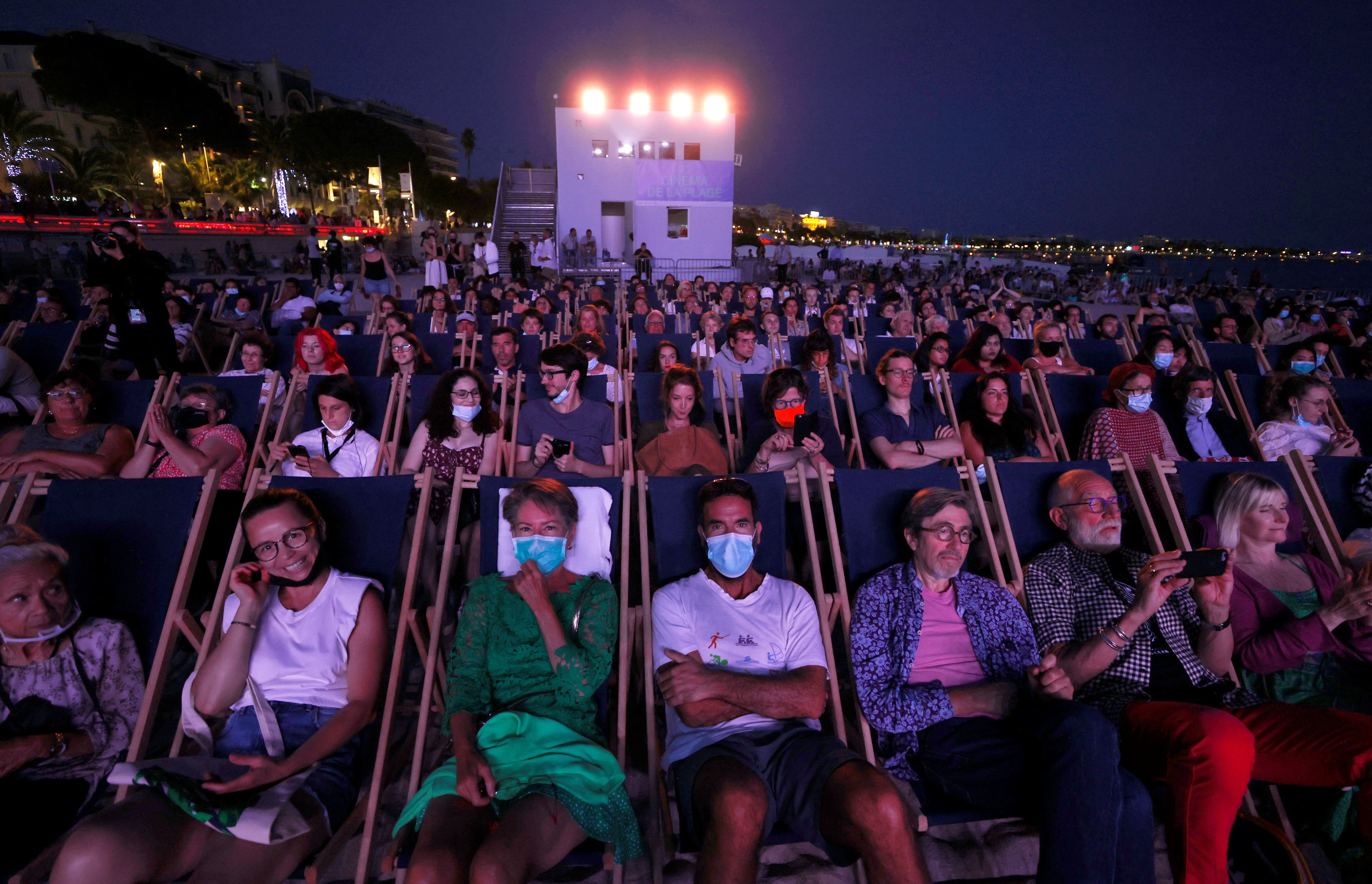 People enjoy a beach front cinema screening at the 74th Cannes on 10 July 2021