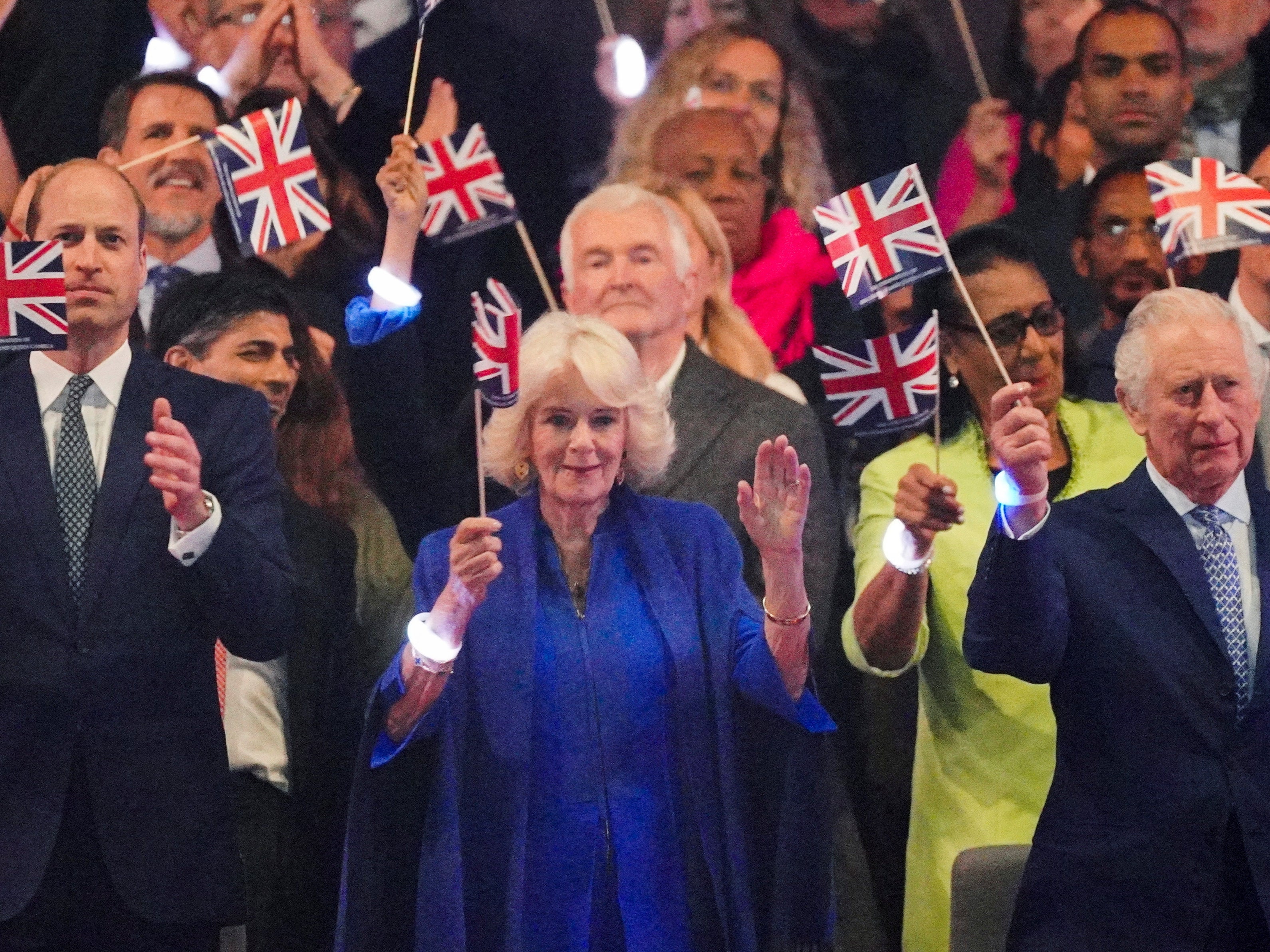 The Prince of Wales, King Charles III and Queen Camilla in the Royal Box viewing the Coronation Concert wearing the wristbands