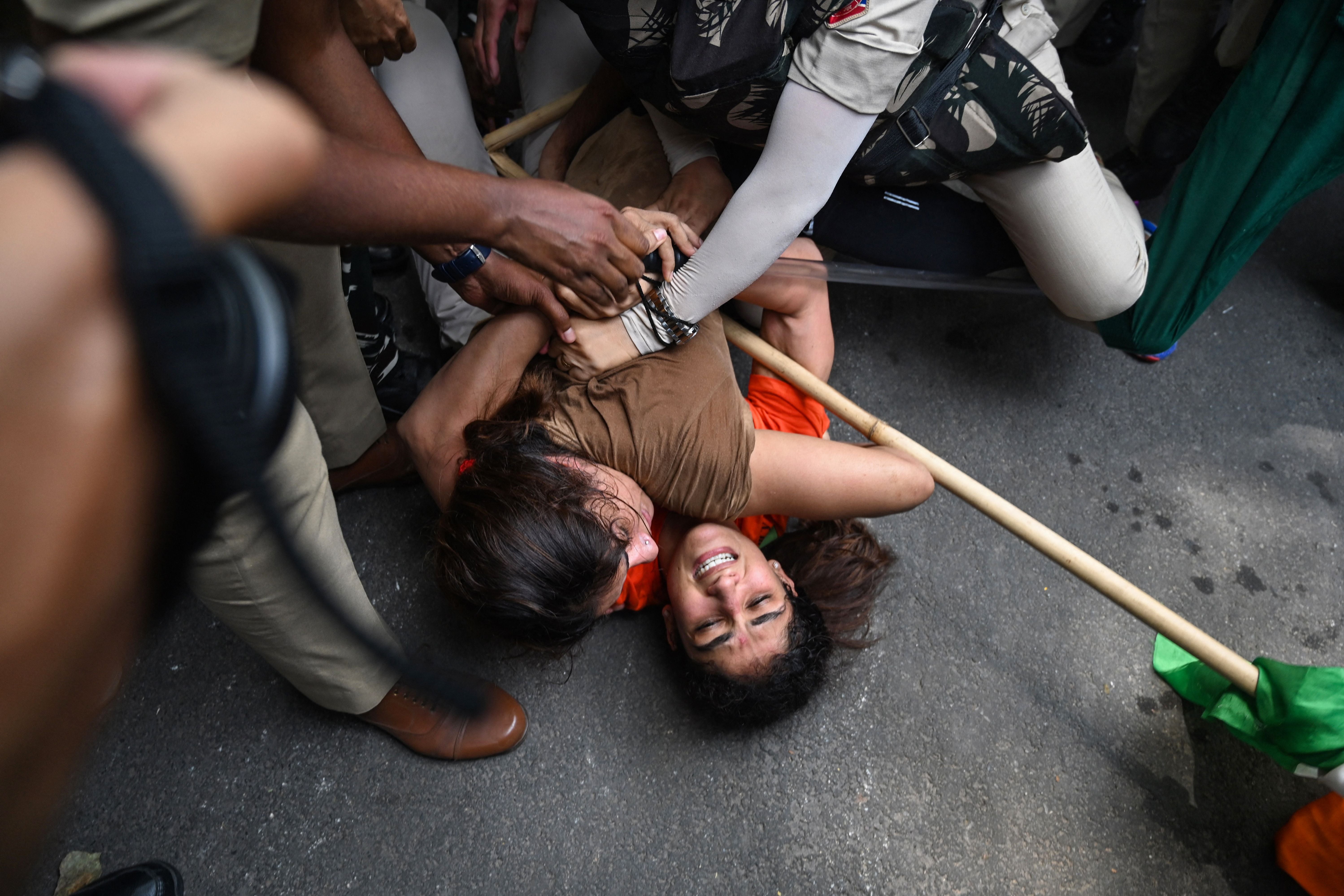 Indian wrestlers Sangeeta Phogat and Vinesh Phogat struggle as they are detained by the police while attempting to march to India's new parliament, just as it was being inaugurated by Prime Minister Narendra Modi, during a protest against Brij Bhushan Singh, the wrestling federation chief, over allegations of sexual harassment and intimidation