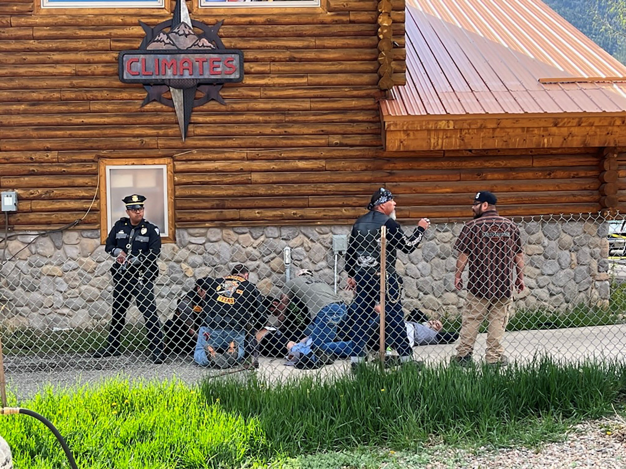 A police officer stands guard as man with a Bandidos MC patch assists a shot biker in Red River, New Mexico after a shootout between members of two motorcycle gangs at an annual Memorial Day motorbike rally