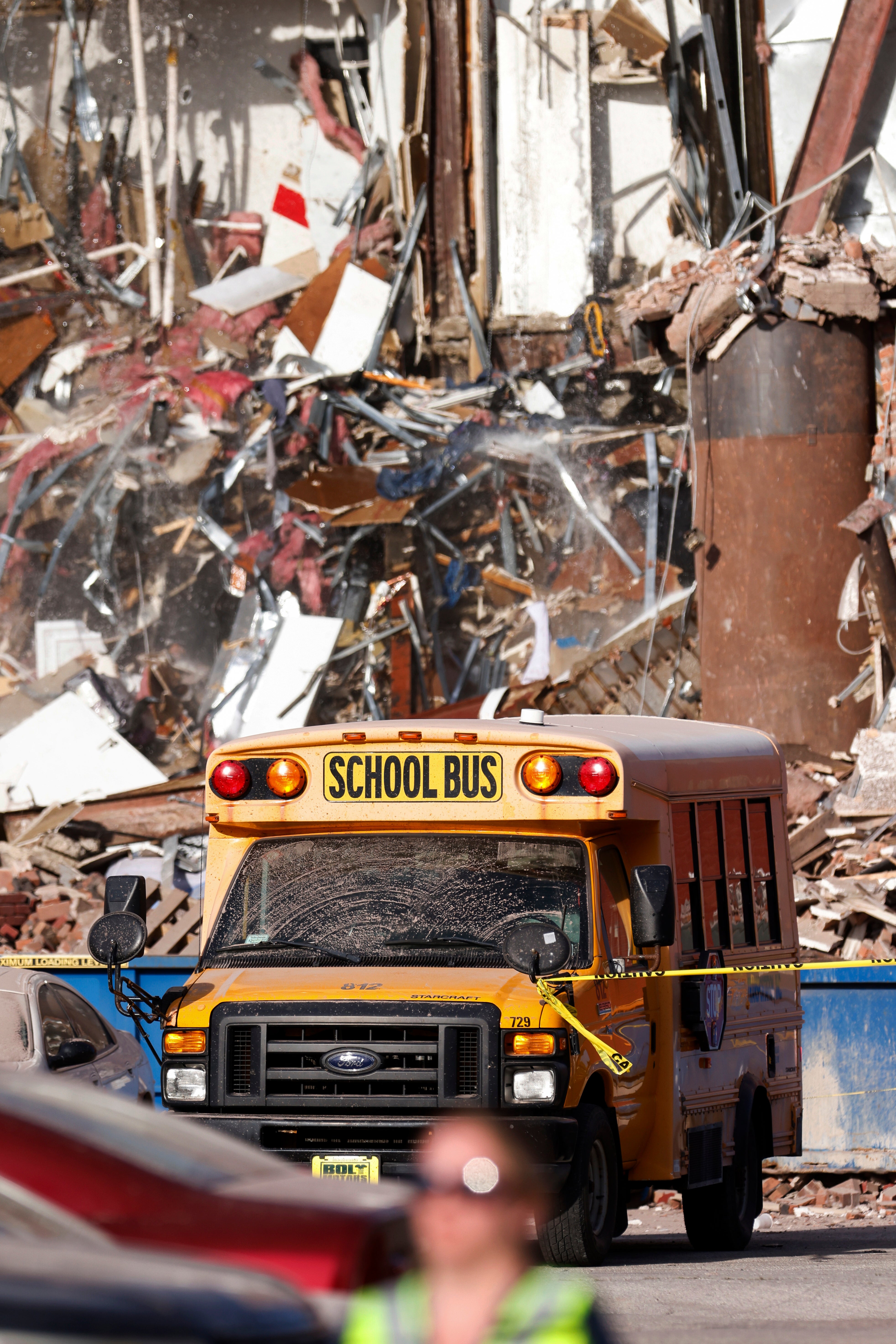 A school bus drives past the rubble after a building collapse on Sunday