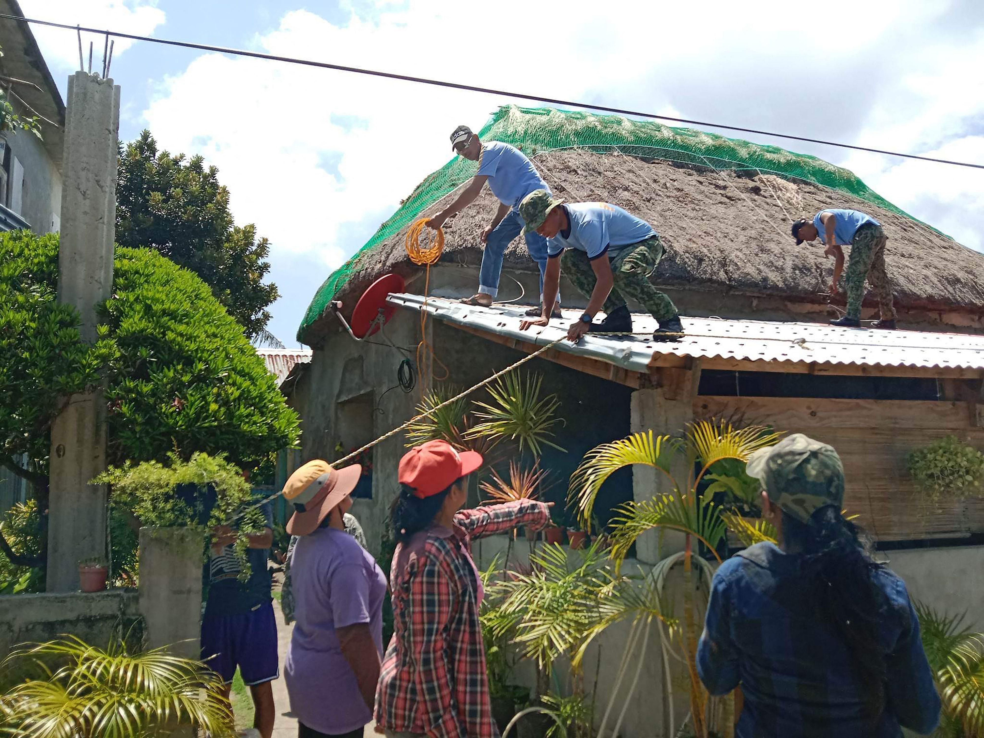 Police personnel helping residents reinforce the roof of their homes in Ivana town, Batanes province, on the very tip of the Philippines, ahead of super Typhoon Mawar grazing the province