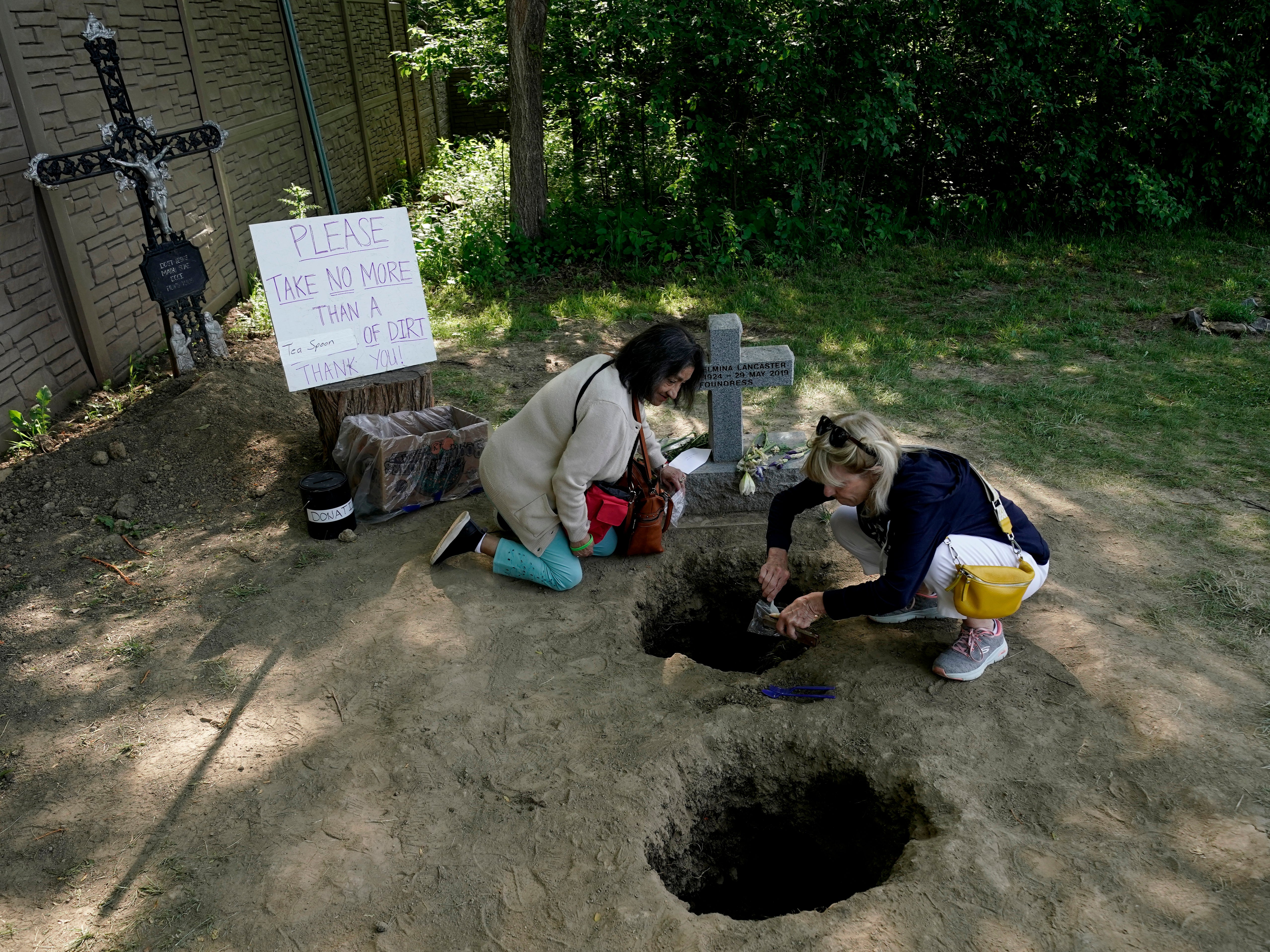 People collect dirt from the gravesite of Sister Wilhelmina Lancaster at the Benedictines of Mary, Queen of Apostles abbey Sunday, May 28, 2023, near Gower, Mo. Hundreds of people visited the small town in Missouri this week to see the nun’s body that has barely decomposed since 2019 (AP Photo/Charlie Riedel)