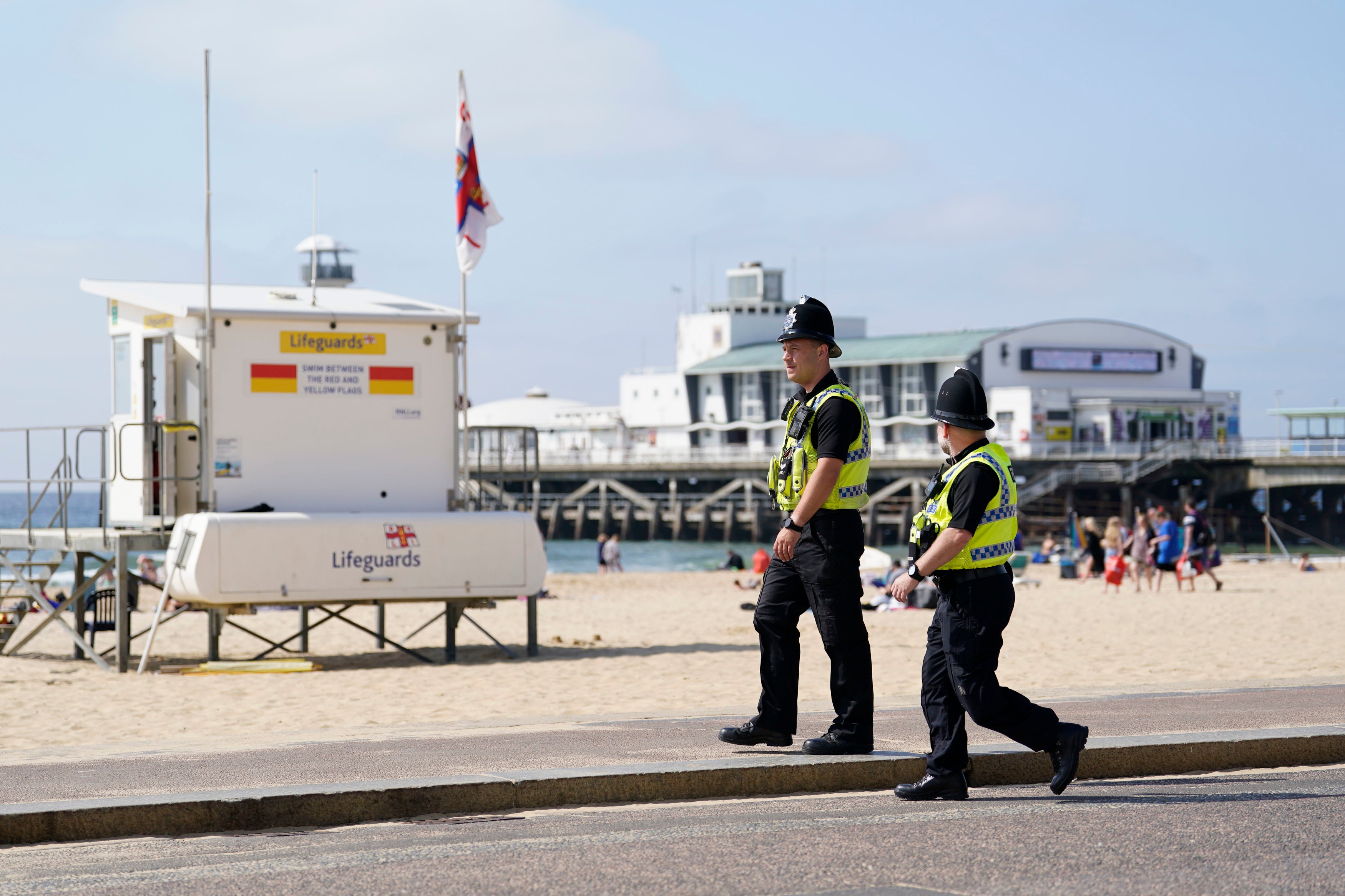 Police walk along Bournemouth beach after incident in which two youngsters died