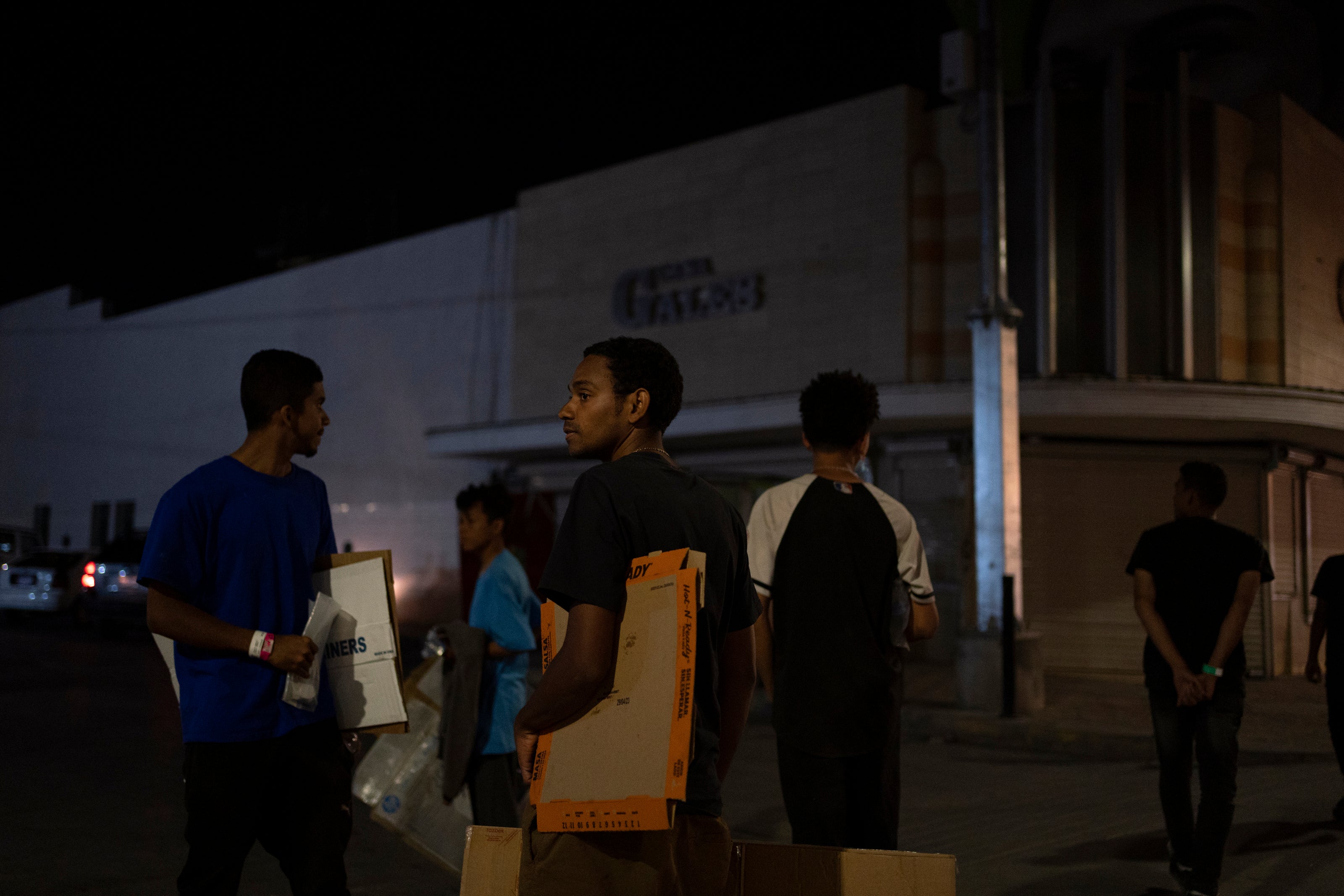 Hours after Title 42 immigration restrictions expired, Venezuelan migrants walk through downtown Juárez early on 12 May carrying the cardboard on which they will sleep