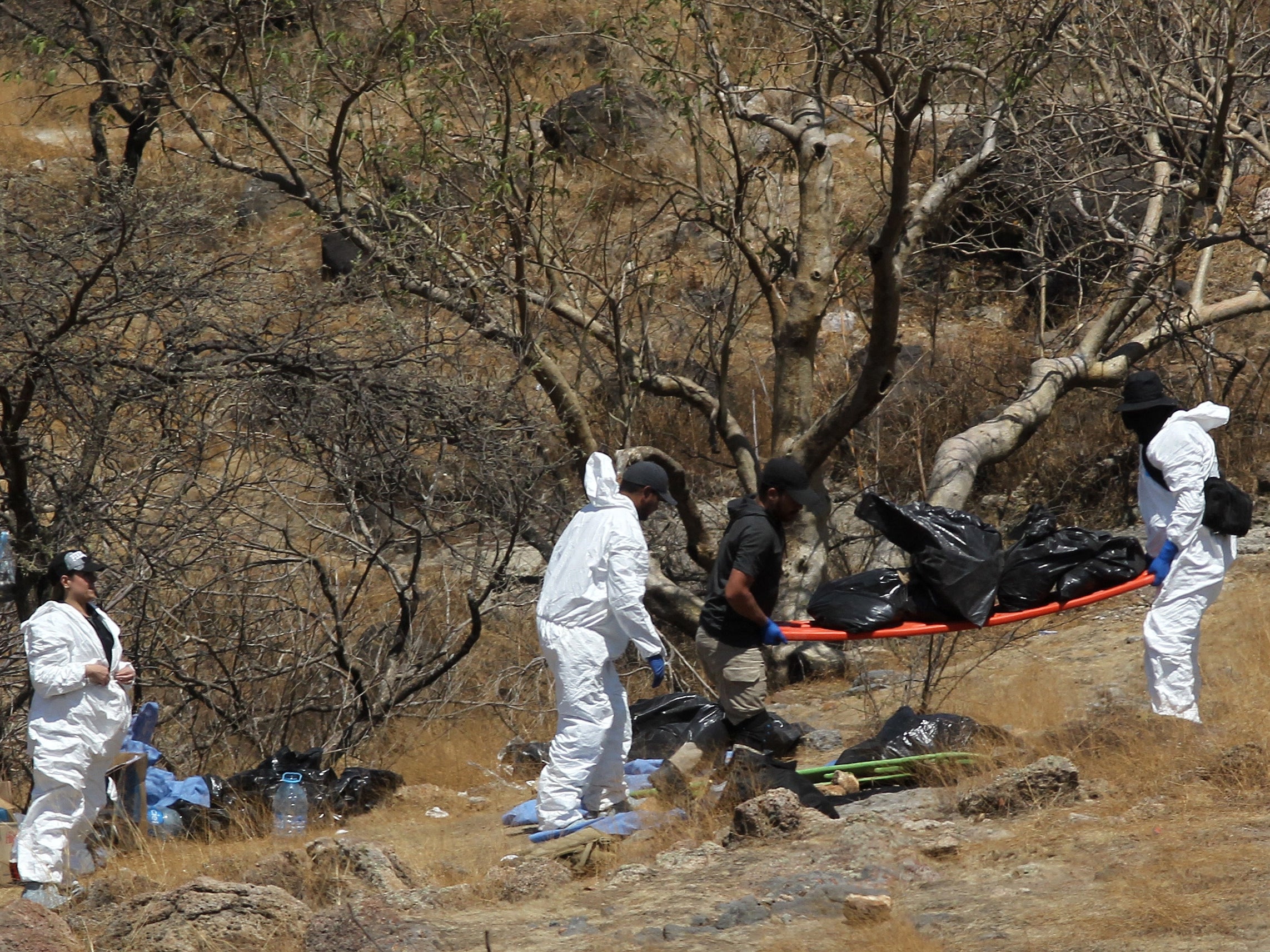 Forensic experts work with several bags of human remains extracted from the bottom of a ravine by a helicopter, which were abandoned at the Mirador Escondido community in Zapopan, Jalisco state, Mexico on May 31, 2023