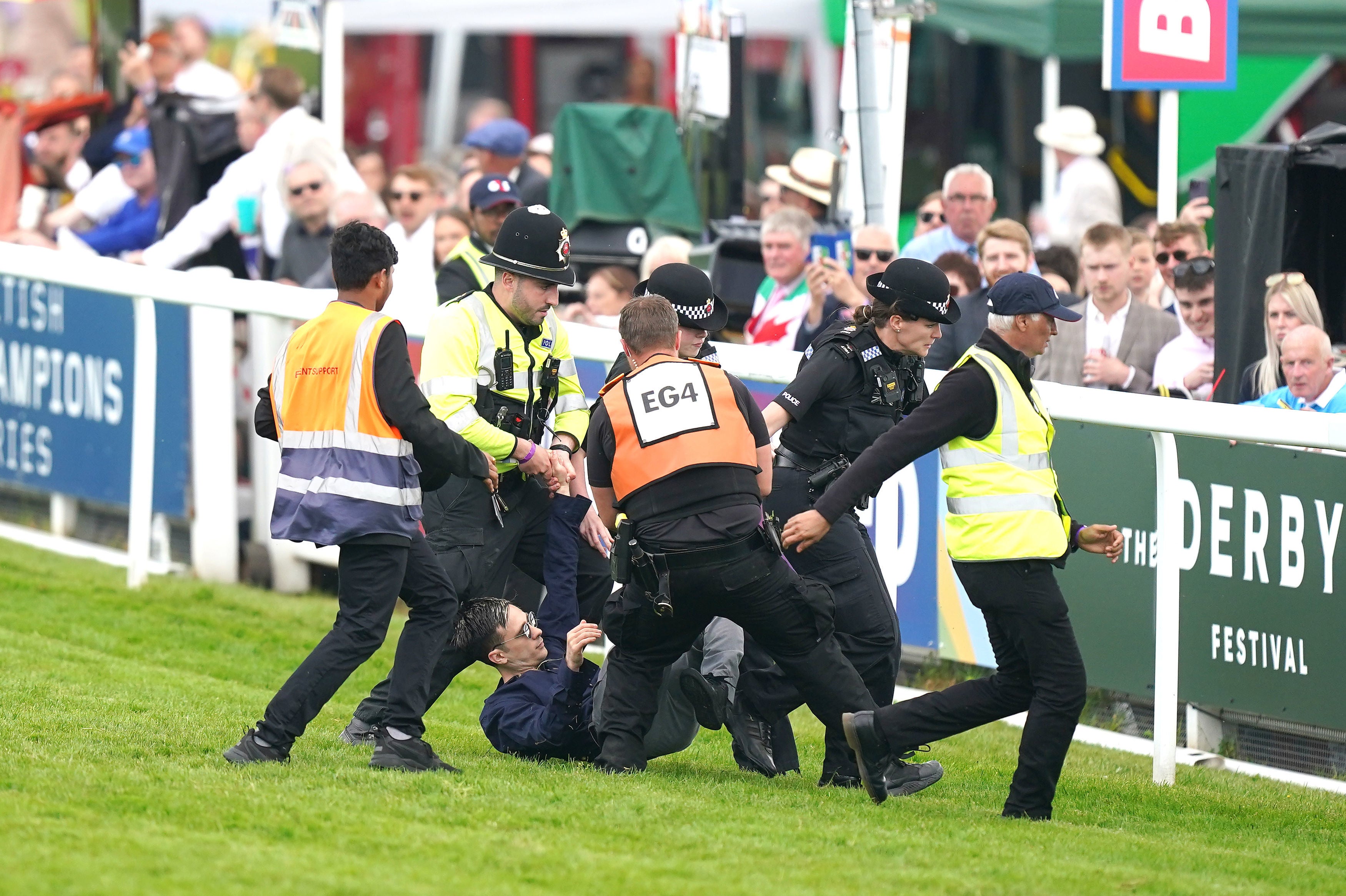 The protester is dragged off the track by police and stewards during the Betfred Derby