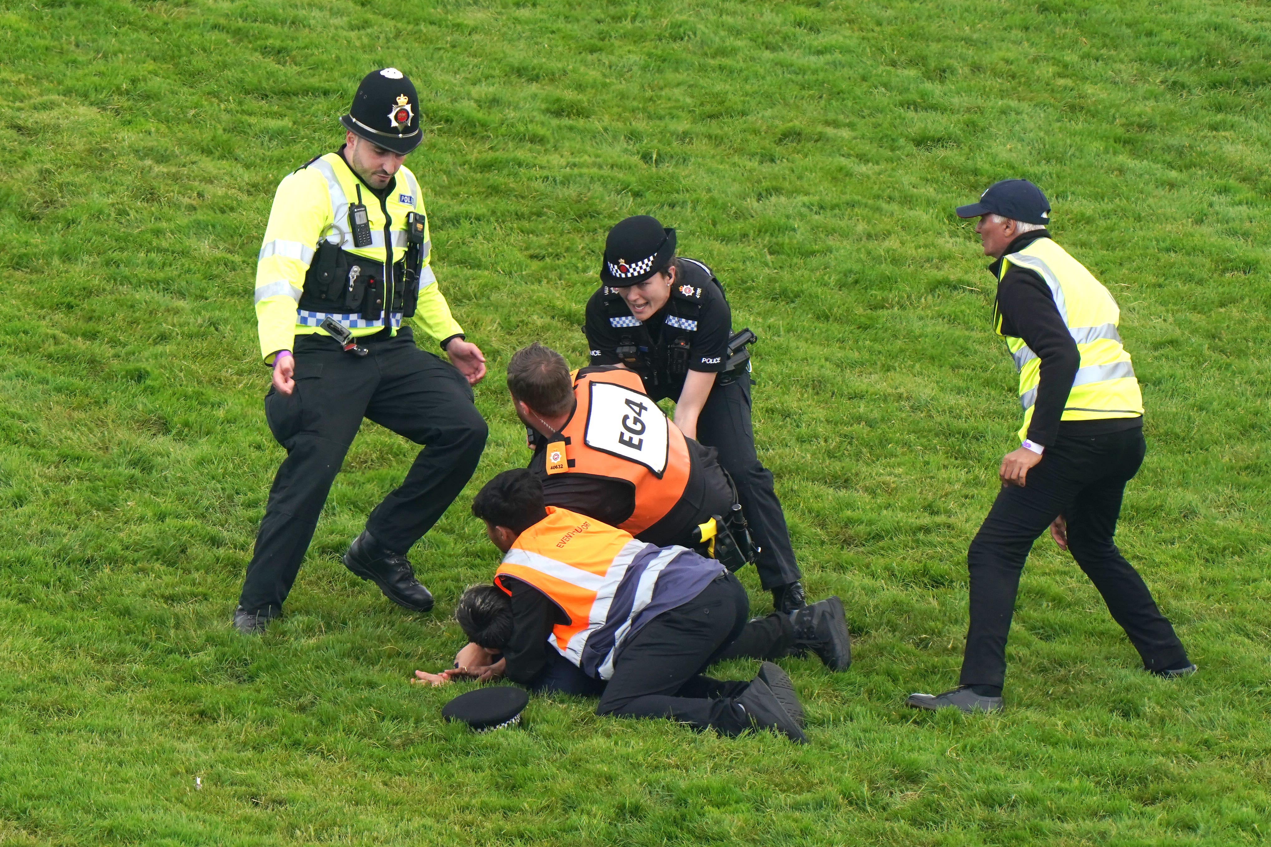 A protester is escorted off the track by police and stewards (Tim Goode/PA)