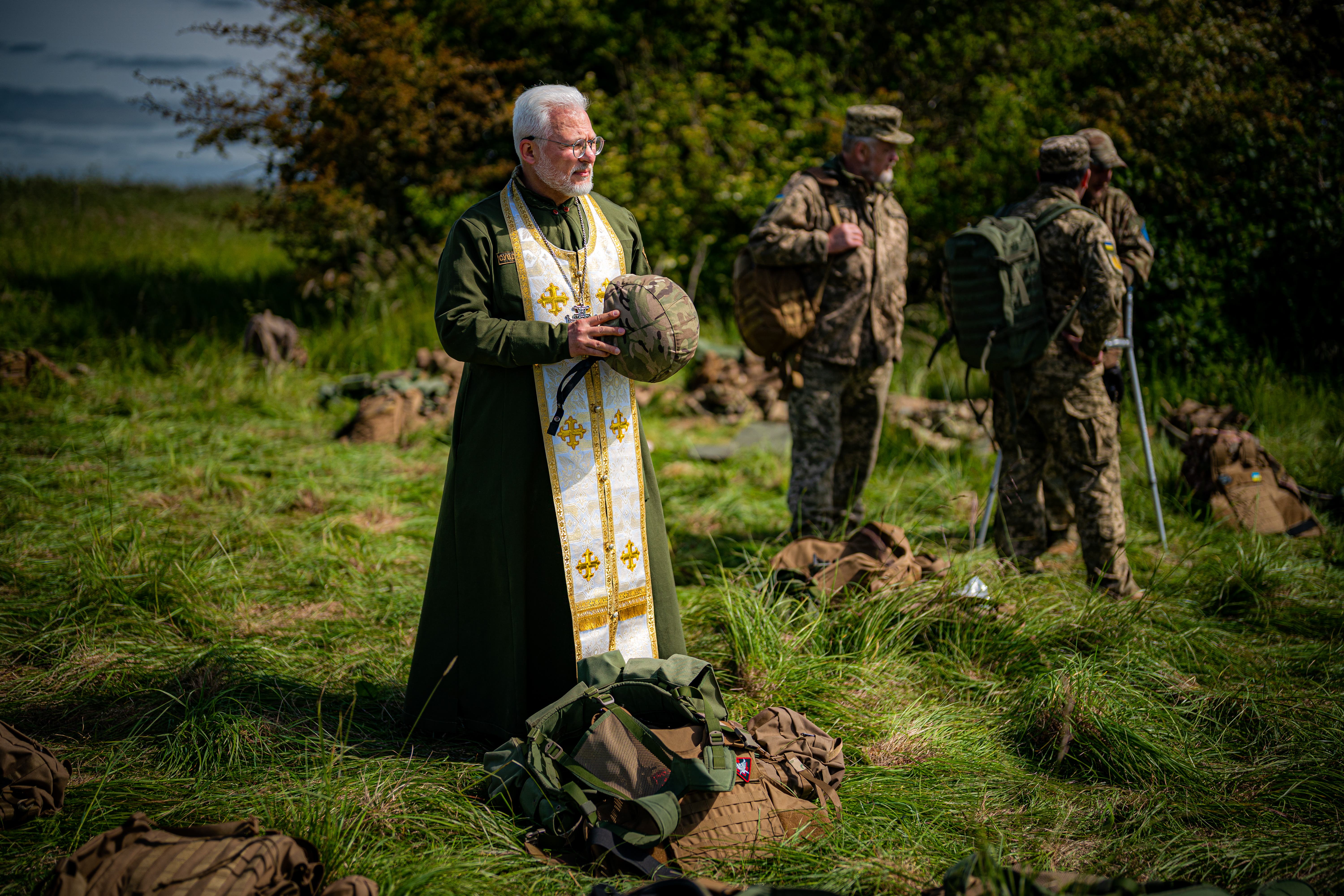 Ukrainian military chaplain 2nd Lt Genadij Rohmanijko, holds a soldier’s helmet on the range (Ben Birchall/PA)