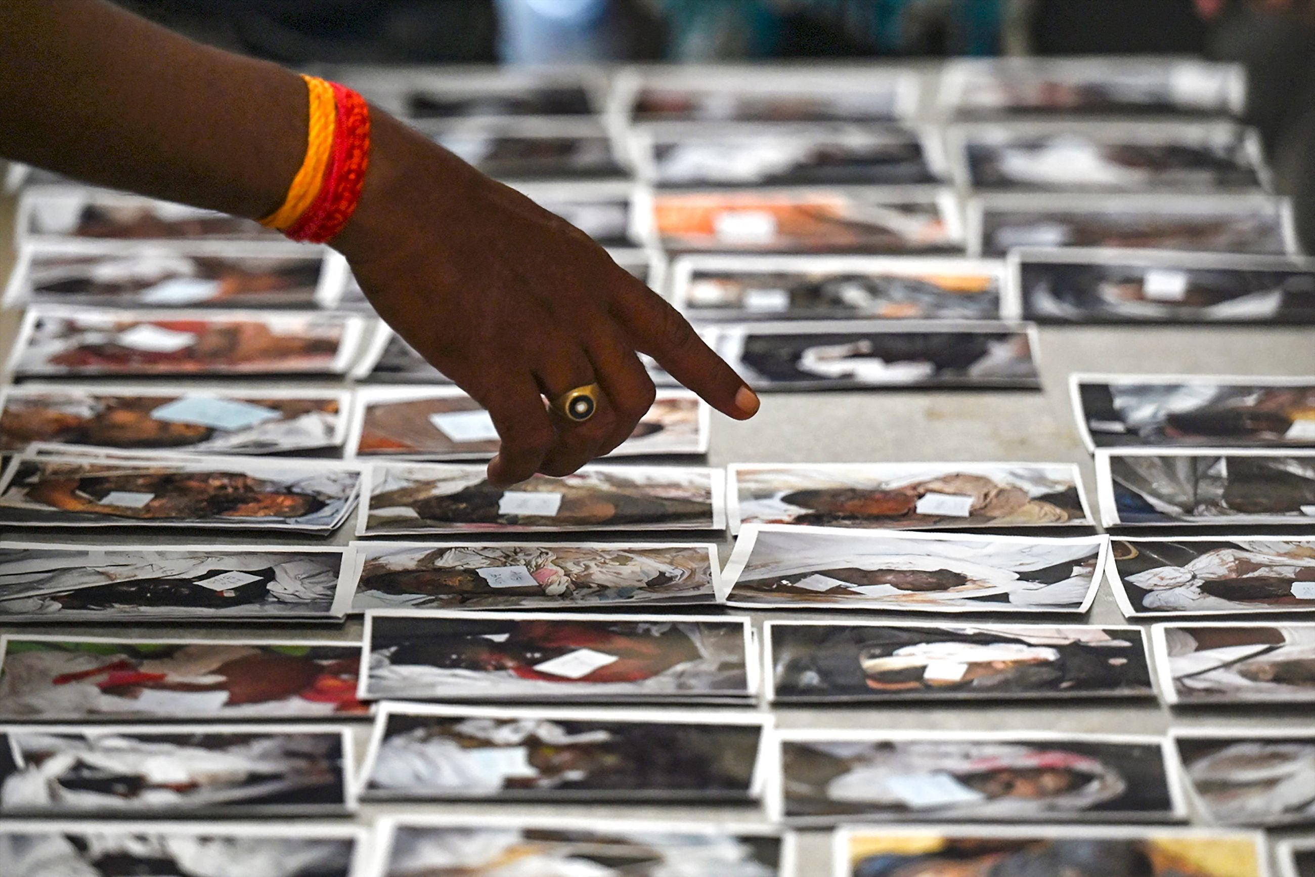 A victim's family member looks at photographs to identify the body at the temporary mortuary