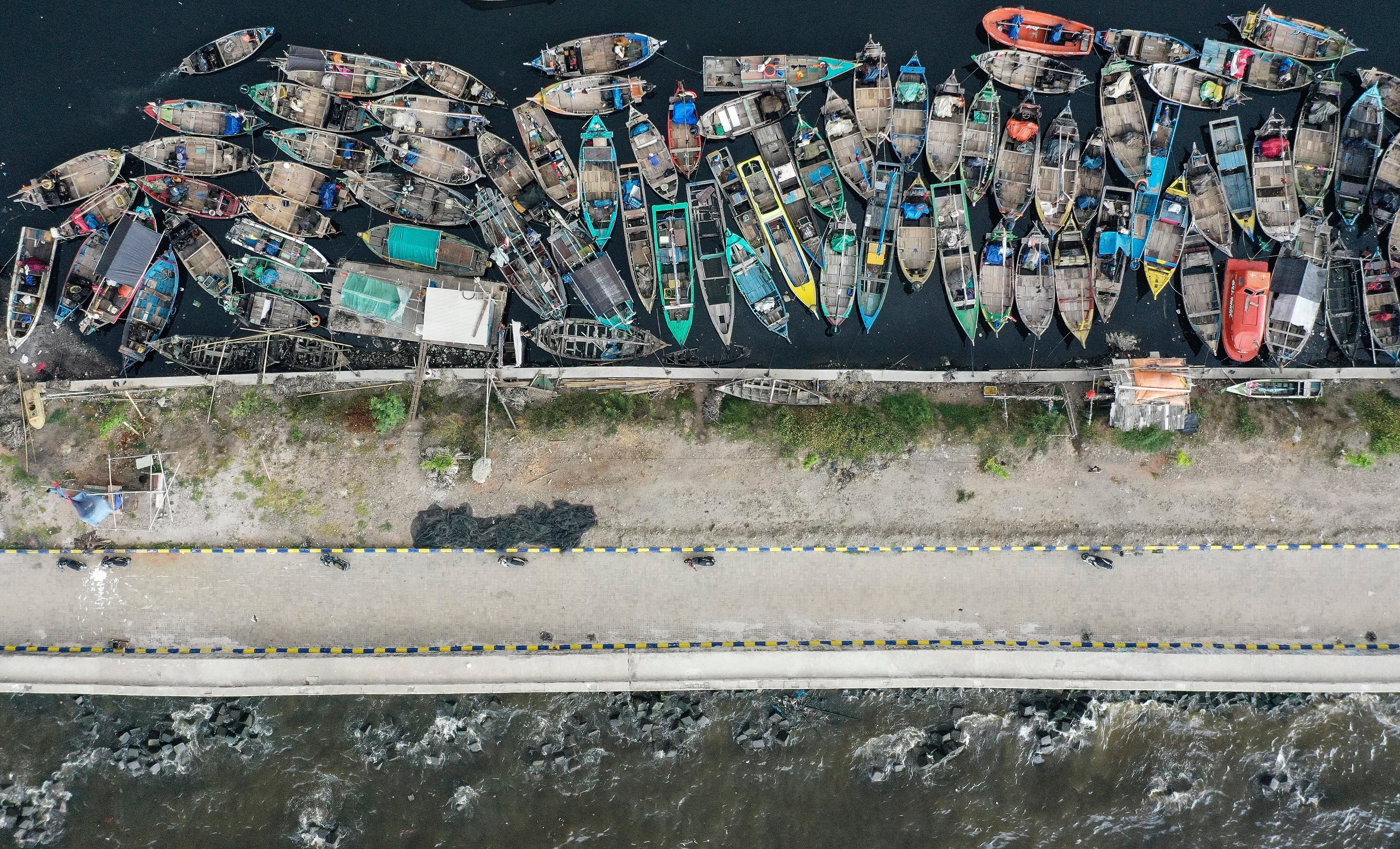 Boats at a fishing dock behind the coastal embankment in Cilincing