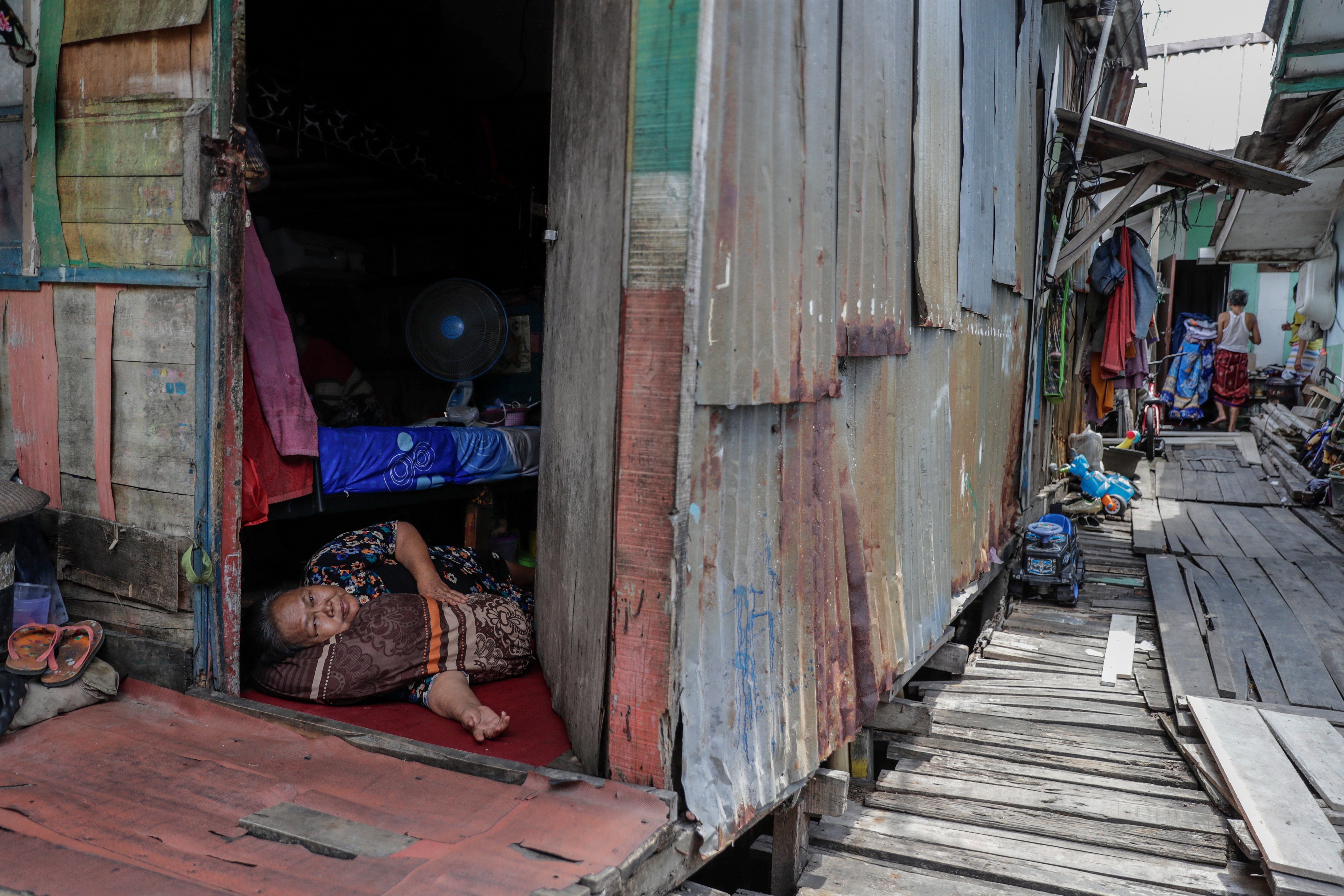 Villager Siti lays on the floor of her wooden house on stilts standing above water at a floating village in Jakarta