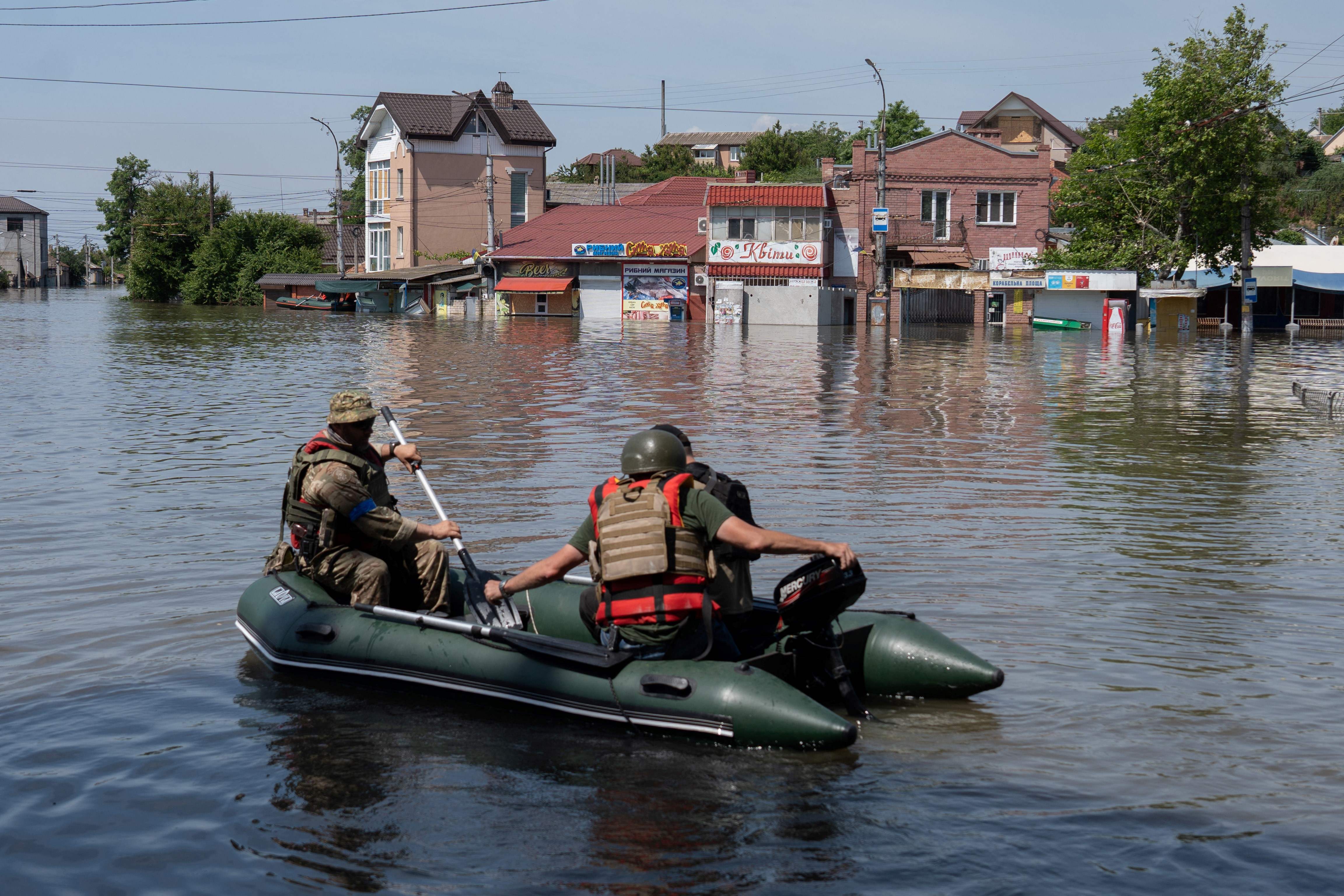 Ukrainian security forces transport local residents in a boat during an evacuation from a flooded area