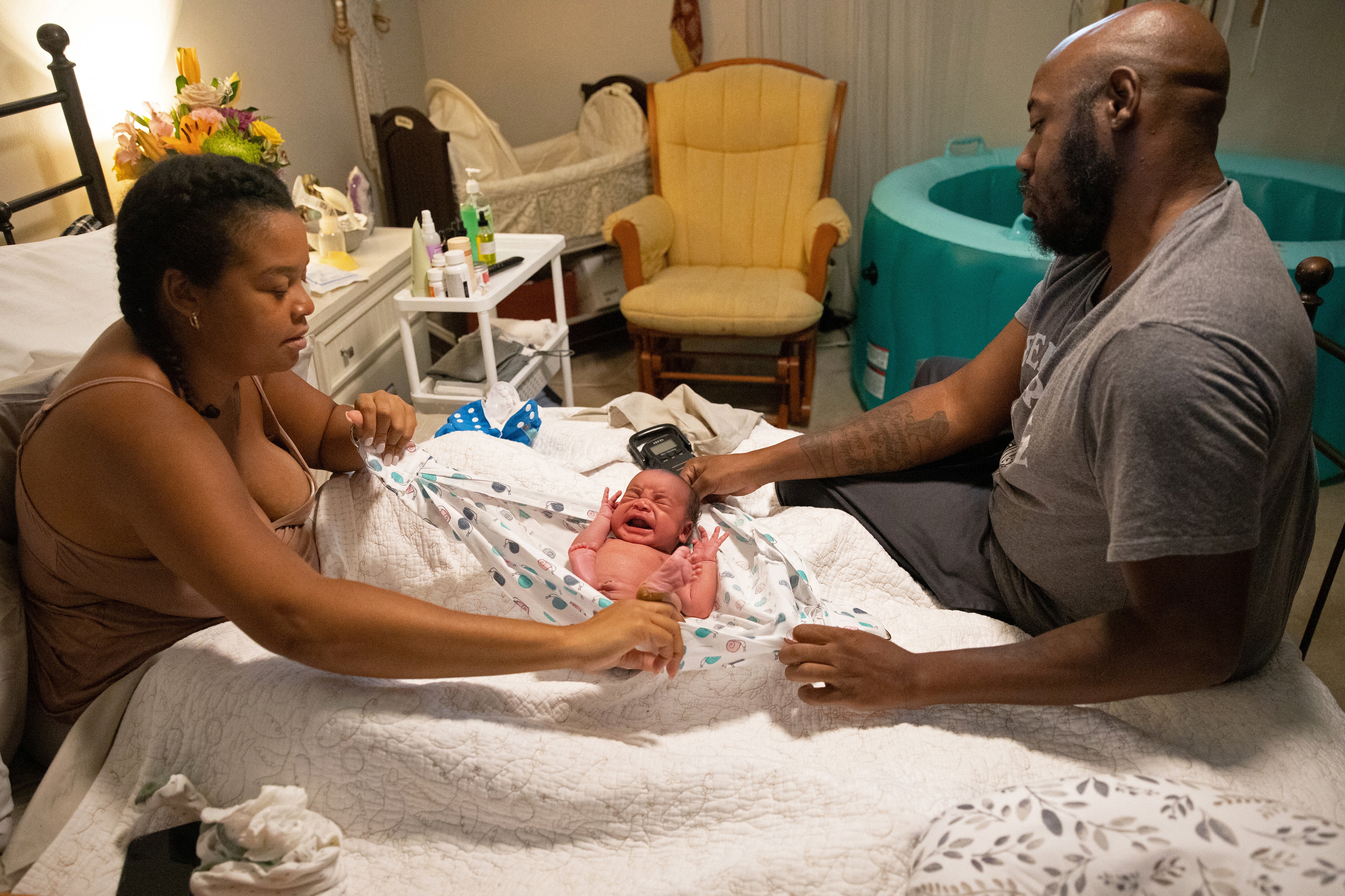 Evan, their crying newborn, is weighed