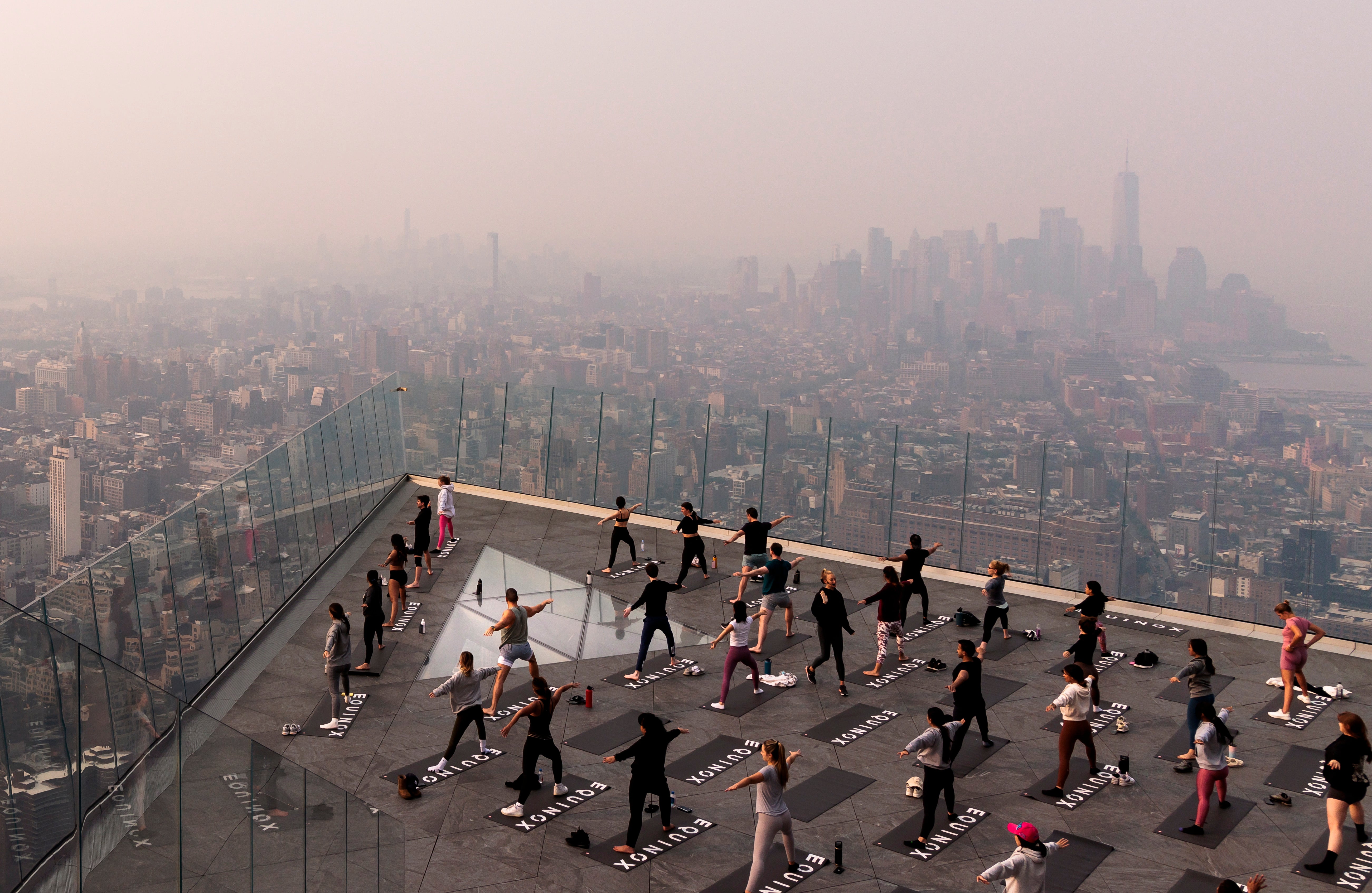 People attend a morning yoga class on The Edge observation deck on the west side of Manhattan as a haze caused by smoke from wildfires burning in Canada hangs over the city