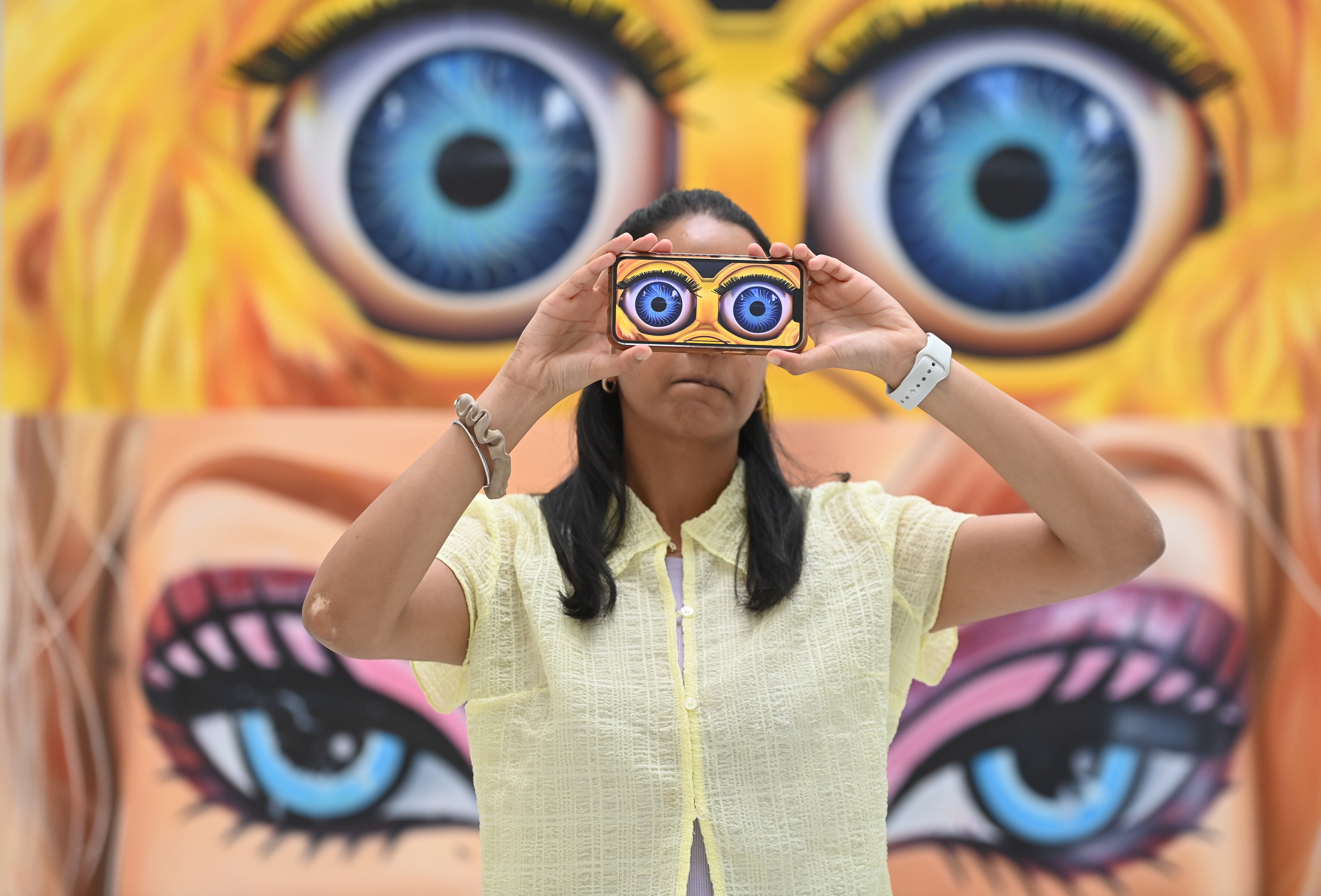 A gallery worker poses with work by artist Rachel Hobkirk during a press preview of The RA Schools Show 2023 at the Royal Academy of Arts in London