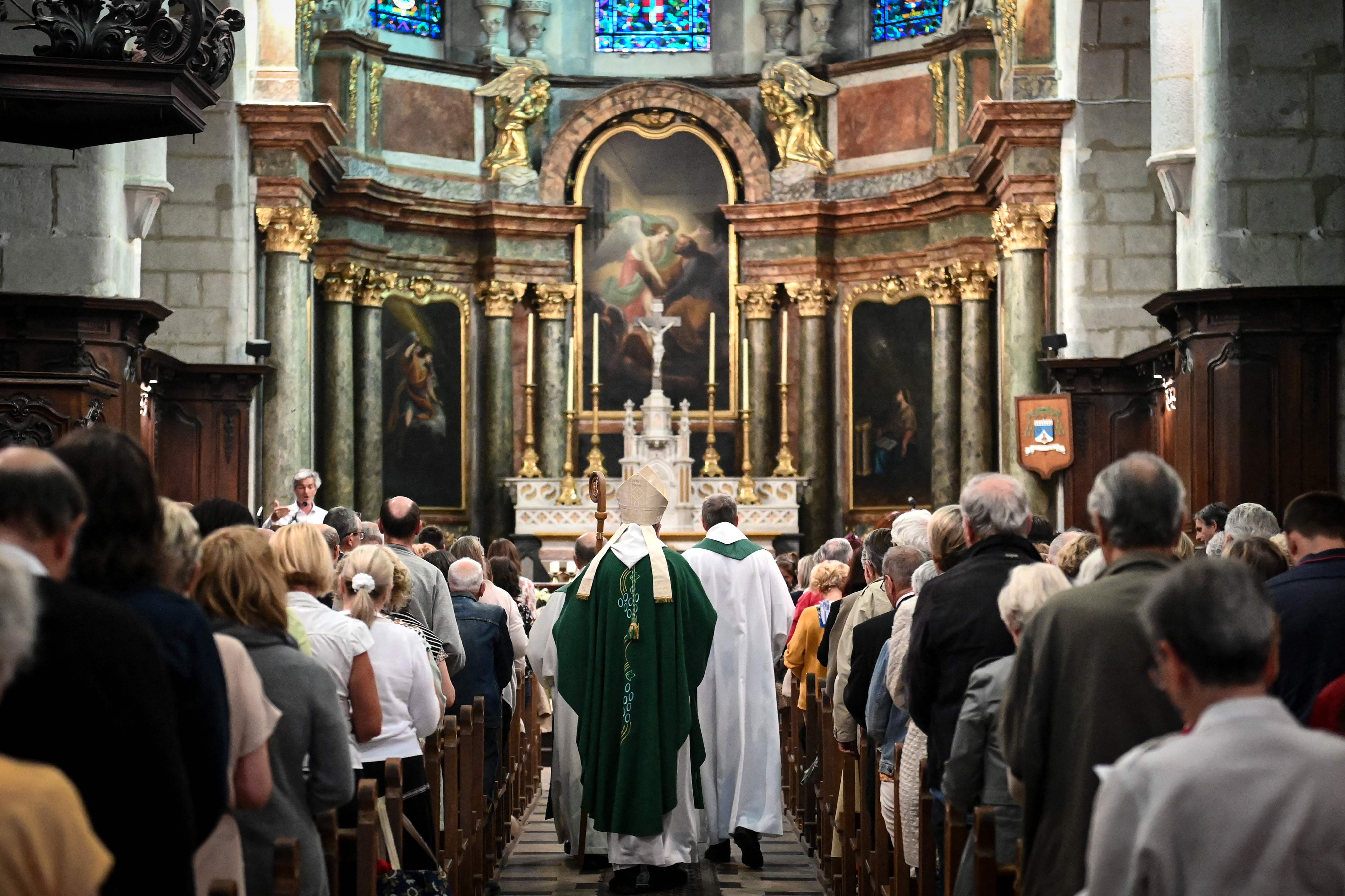 Father Didier Milani (C-L) and Bishop Yves Le Saux (C) arrive for a mass in Annecy