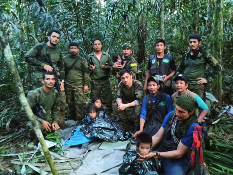 In this photo released by Colombia's Armed Forces Press Office, soldiers and Indigenous men pose for a photo with the four Indigenous children who were missing after a deadly plane crash, in the Solano jungle, Caqueta state, Colombia.