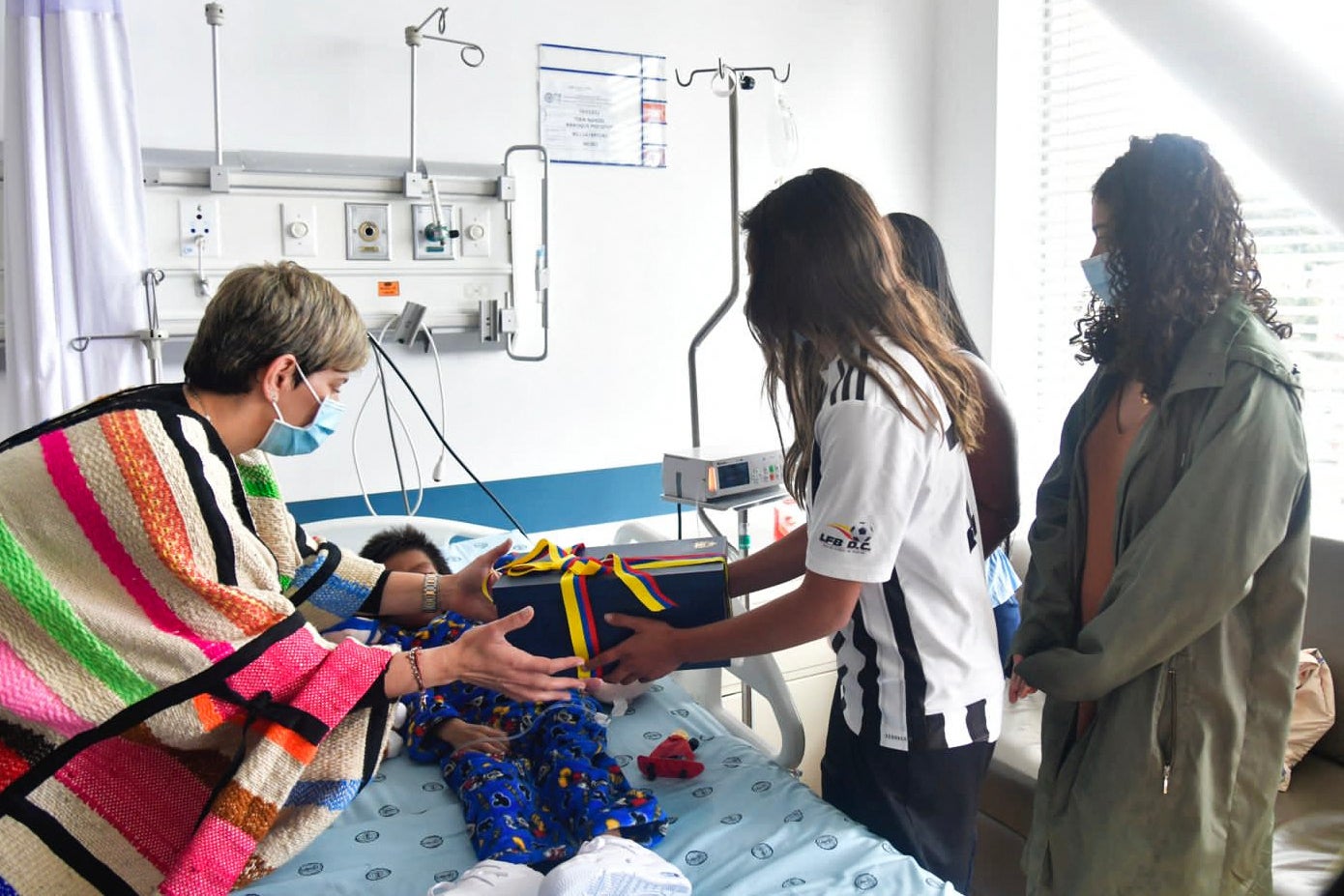 Colombia's first lady Veronica Alcocer, left, presents a gift to one of the children