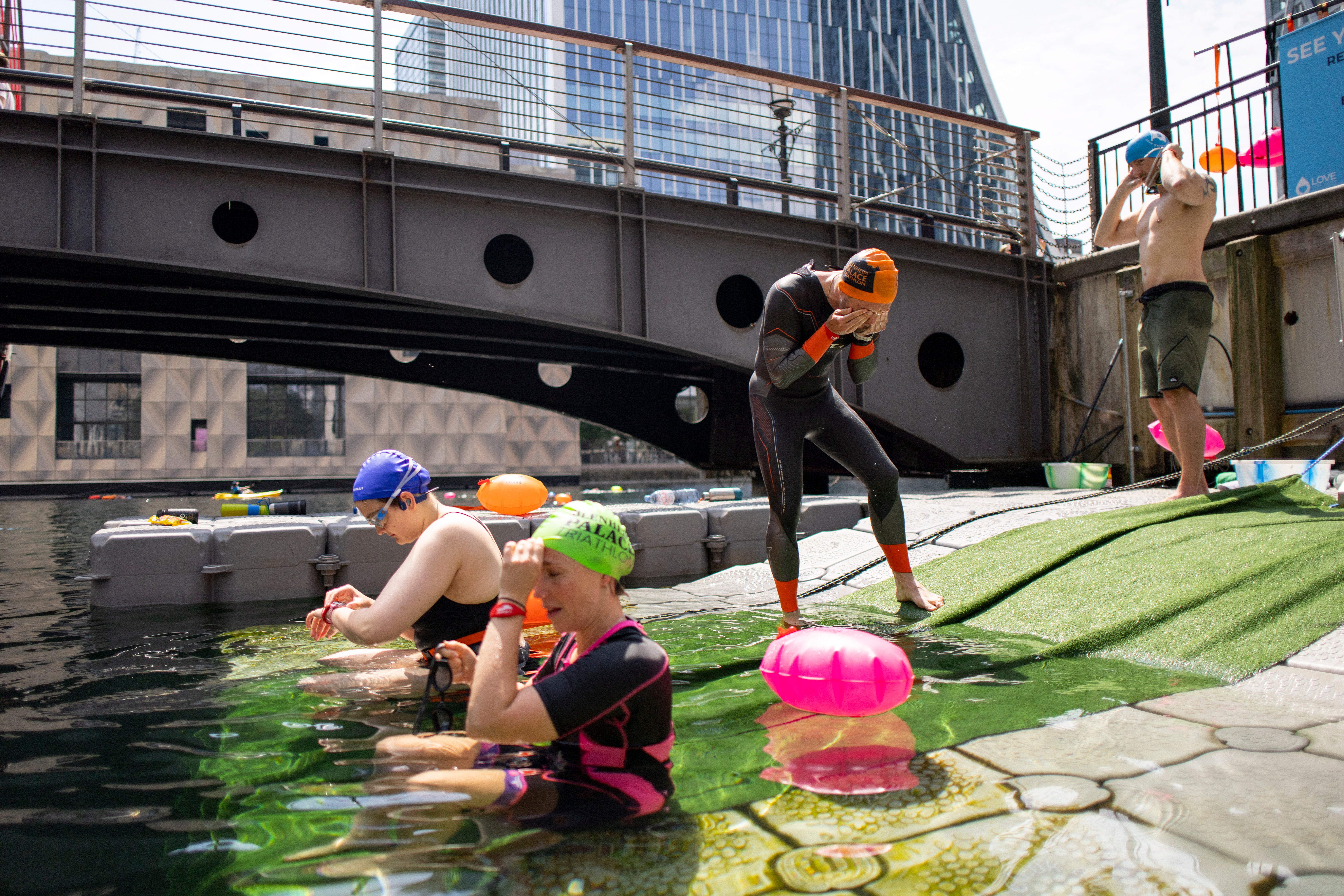 People prepare to swim at Canary Wharf's Middle Dock swimming area during a heatwave in London, Britain,