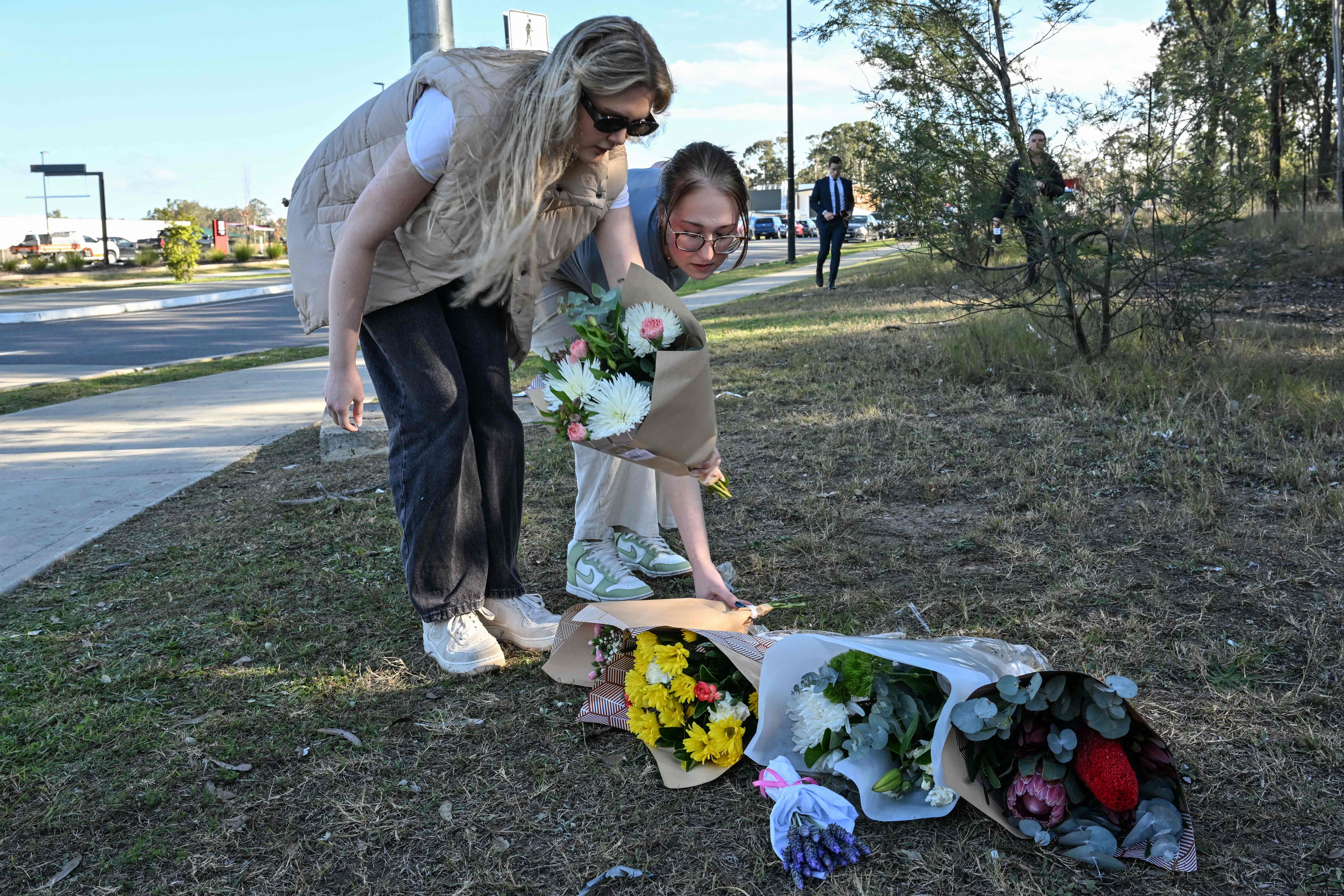 People place flowers next to a road some 500 meters from the site of a bus crash