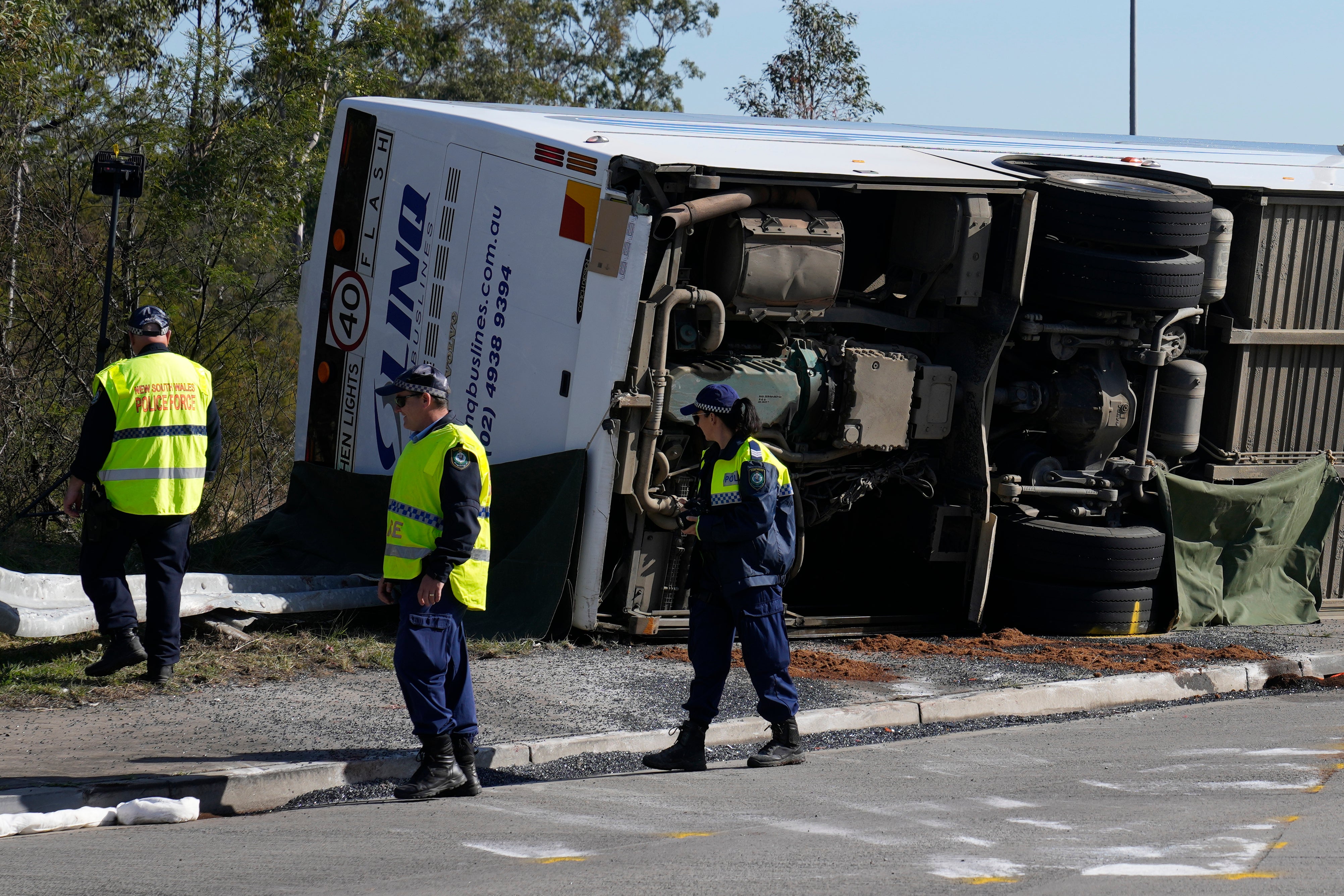 Police inspect a bus in its side near the town of Greta following a crash in the Hunter Valley, north of Sydney