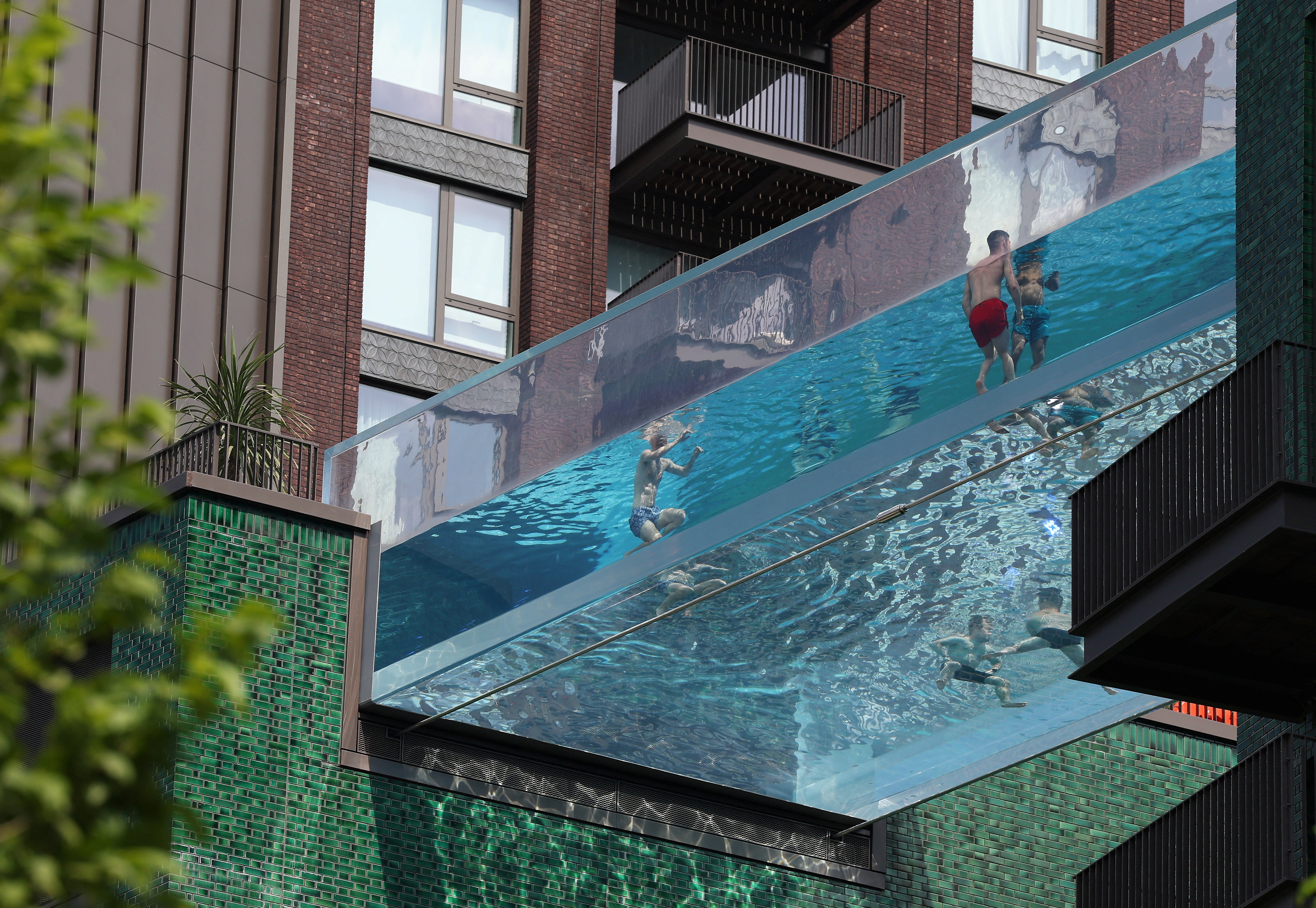 People relax in a swimming pool suspended between two buildings as hot weather continues, in London, Britain, 12 June 2023