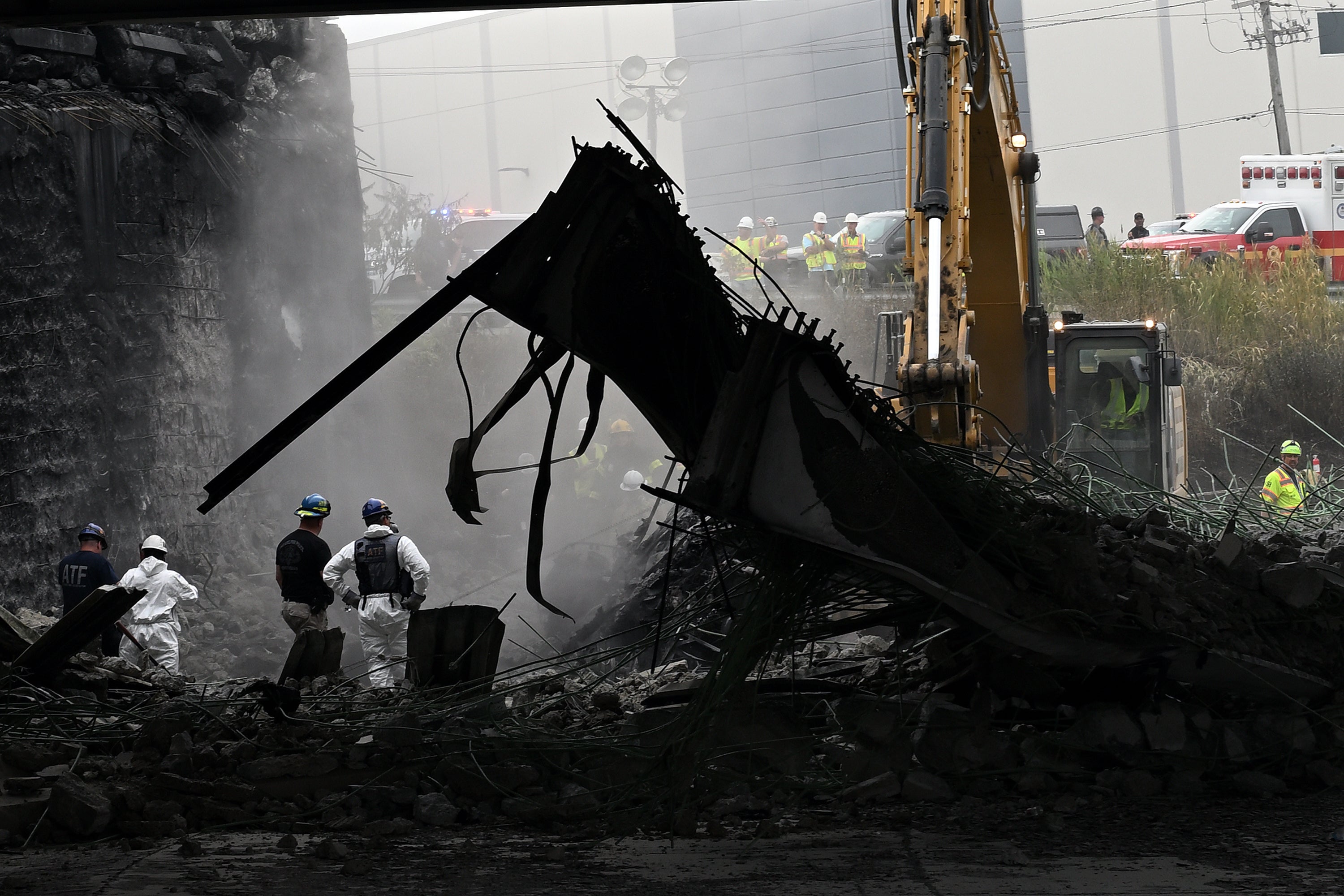 Workers inspect and clear debris from a section of the bridge that collapsed on Interstate 95 after an oil tanker explosion in Philadelphia, Pennsylvania