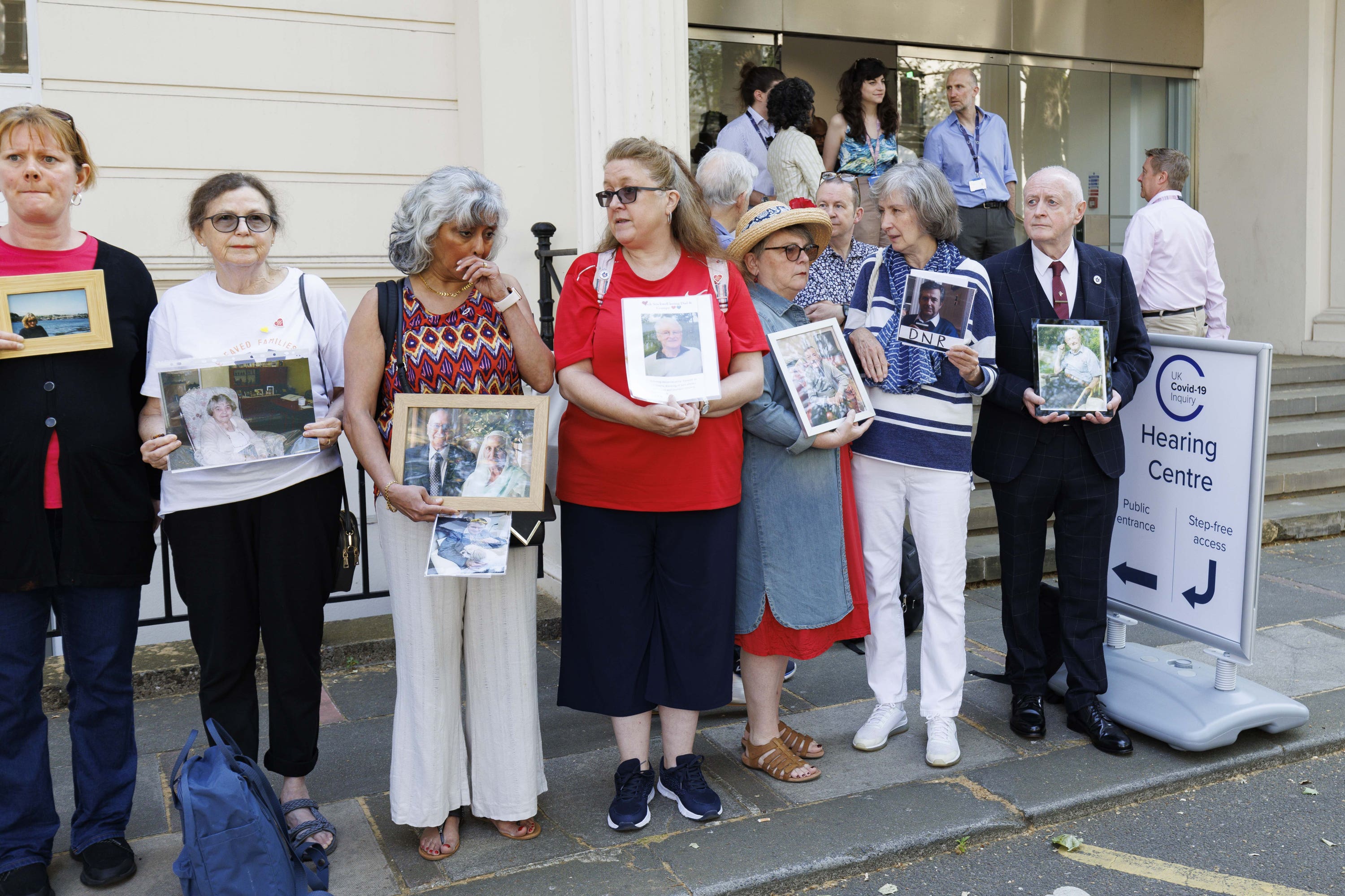 People hold pictures of loved ones lost during the pandemic outside the UK Covid-19 Inquiry at Dorland House in London