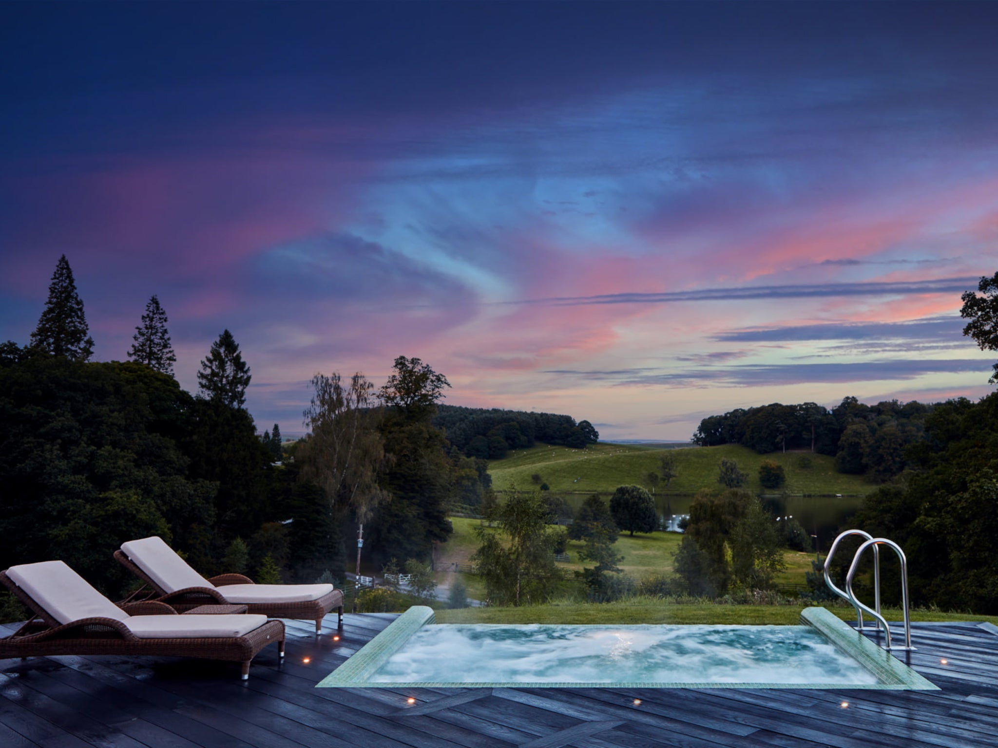 The outdoor infinity pool at Coniston Hotel overlooks rolling hills and a tranquil lake