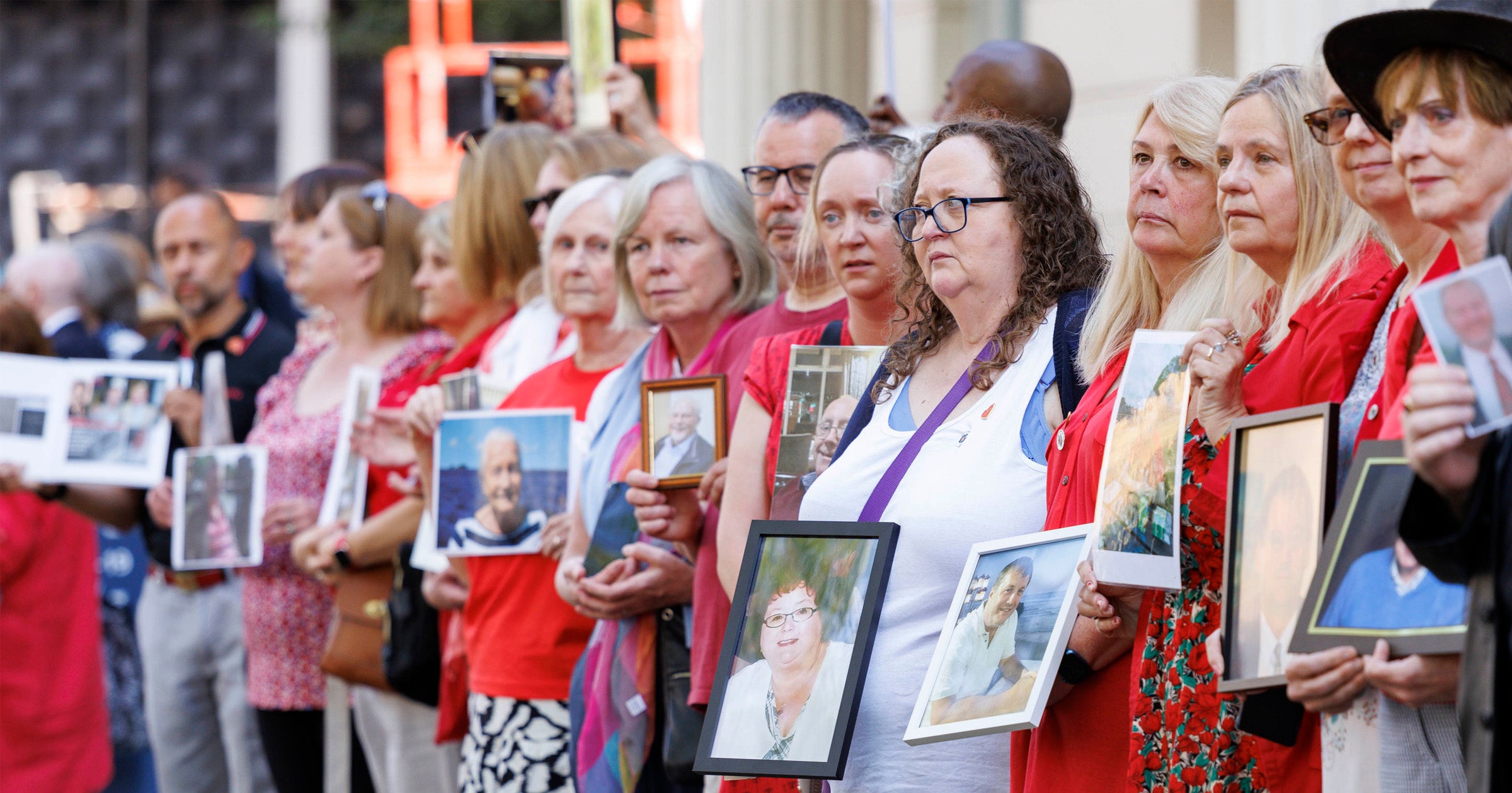 People hold pictures of loved ones lost during the pandemic outside the UK Covid-19 Inquiry at Dorland House in London