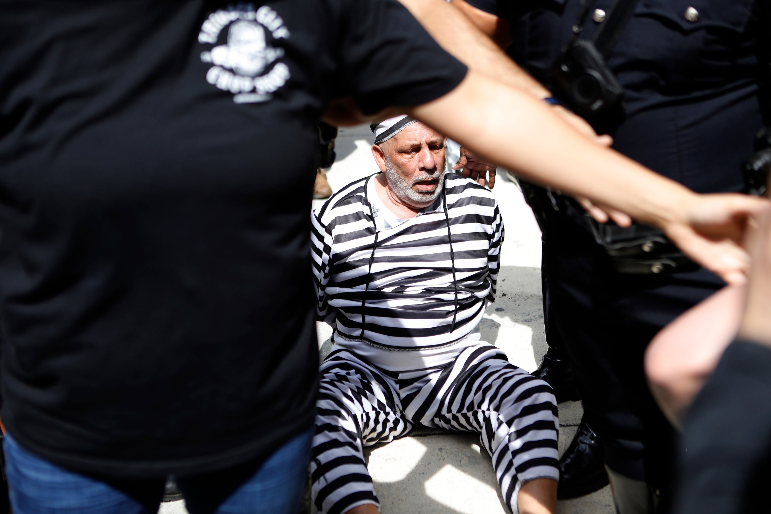 Dominic Santana of Miami is detained by Miami police after trying to block former President Donald Trump's motorcade