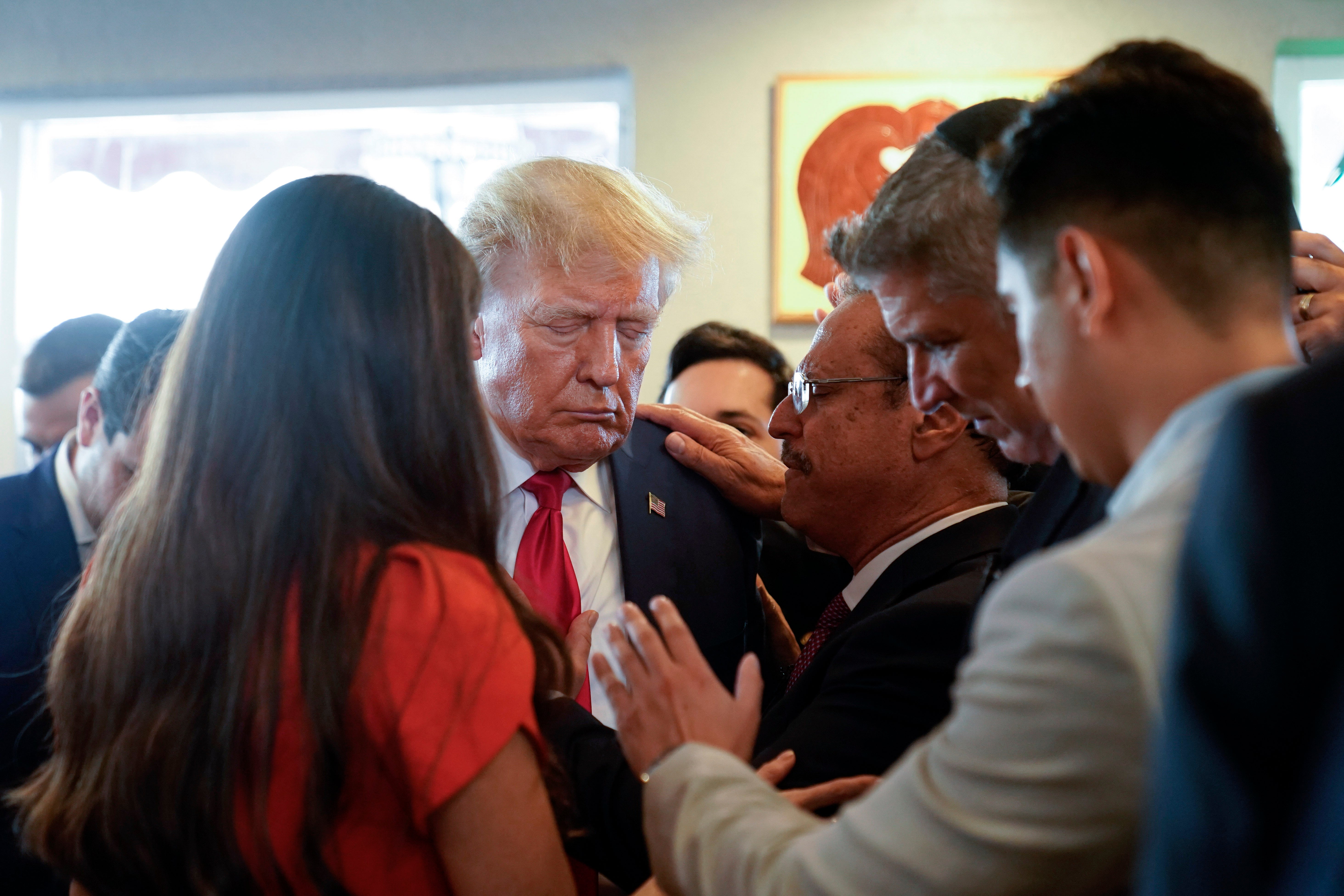 Trump prays with pastor Mario Bramnick, third from right, and others at Versailles restaurant in Miami after his court appearance