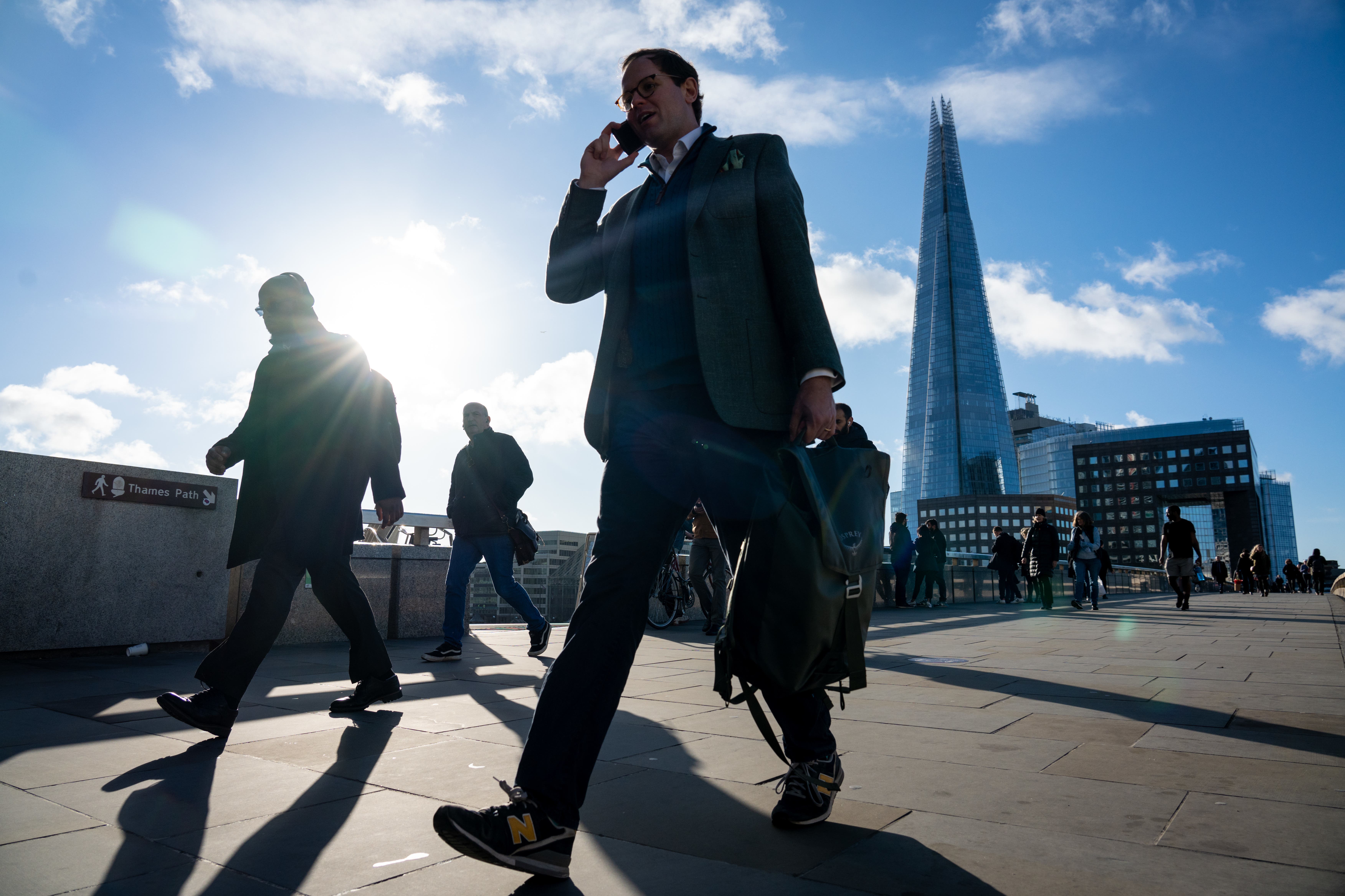 Commuters walk across London Bridge, in central London