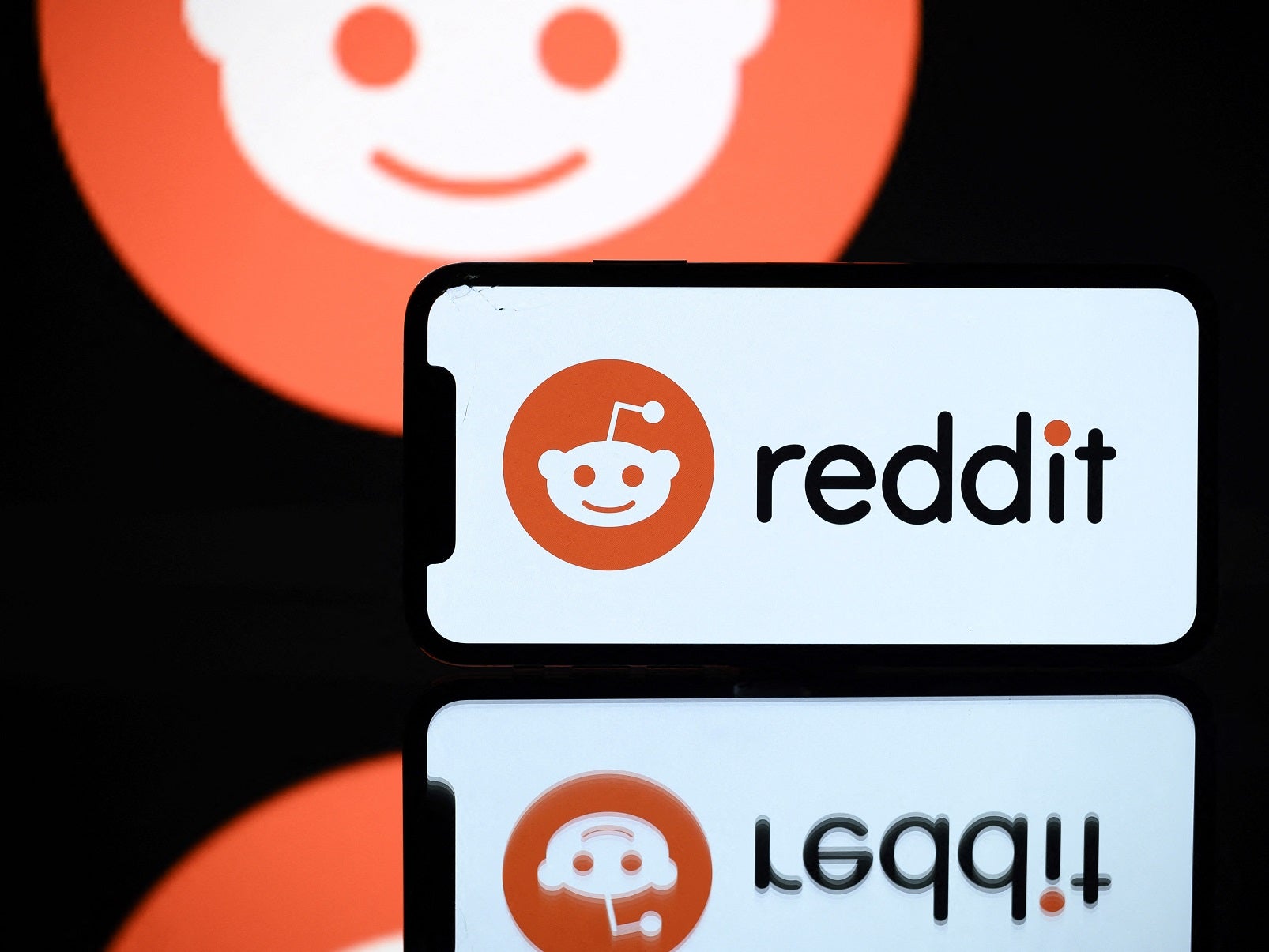 A picture taken on 5 October, 2021 in Toulouse shows the logo of Reddit social media displayed by a by a tablet and a smartphone