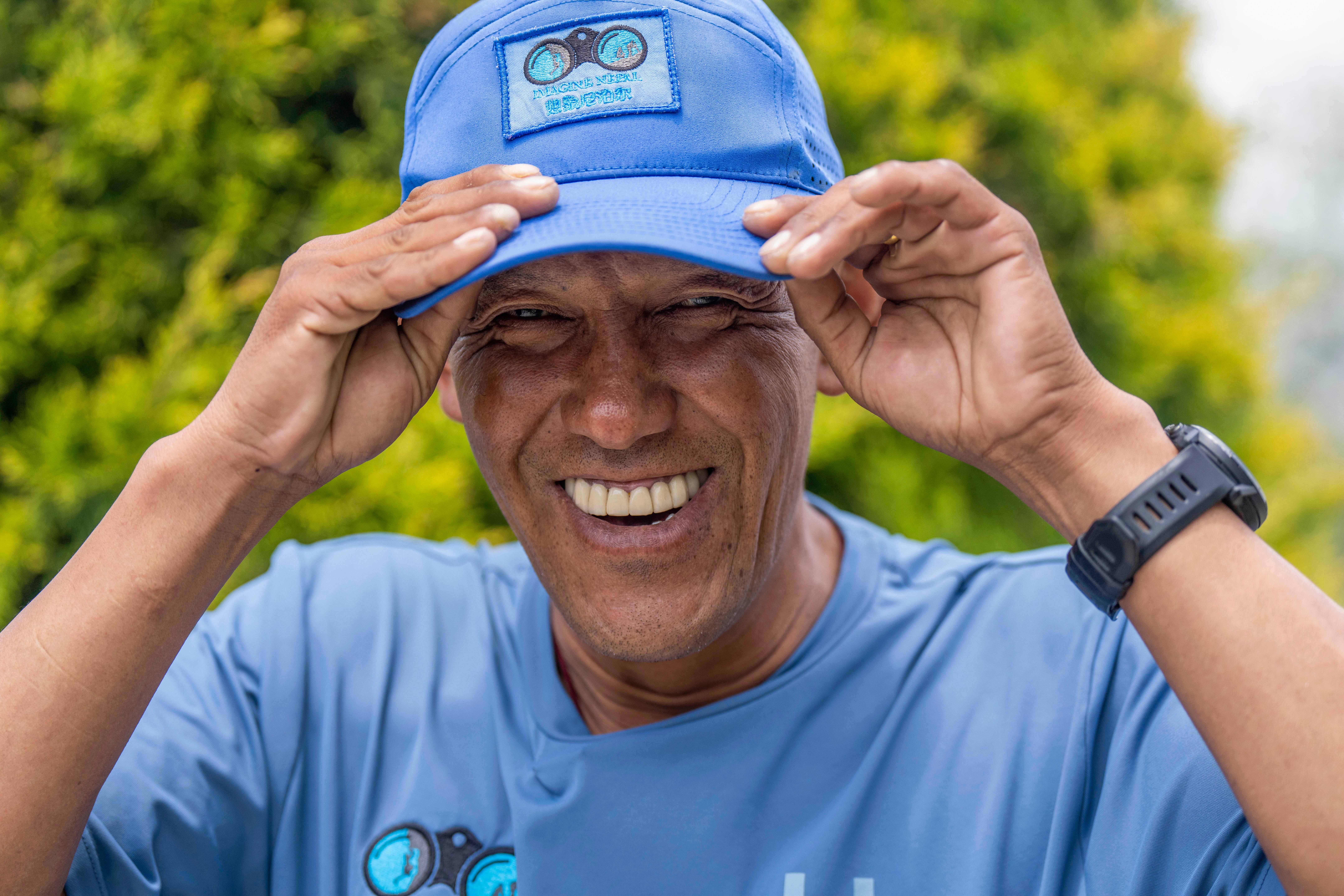 Sherpa guide Pasang Dawa, 48, adjusts his hat as he poses for a photograph during an interview with the Associated Press in Kathmandu, Nepal, Thursday, June 15, 2023 (AP Photo/Niranjan Shrestha)