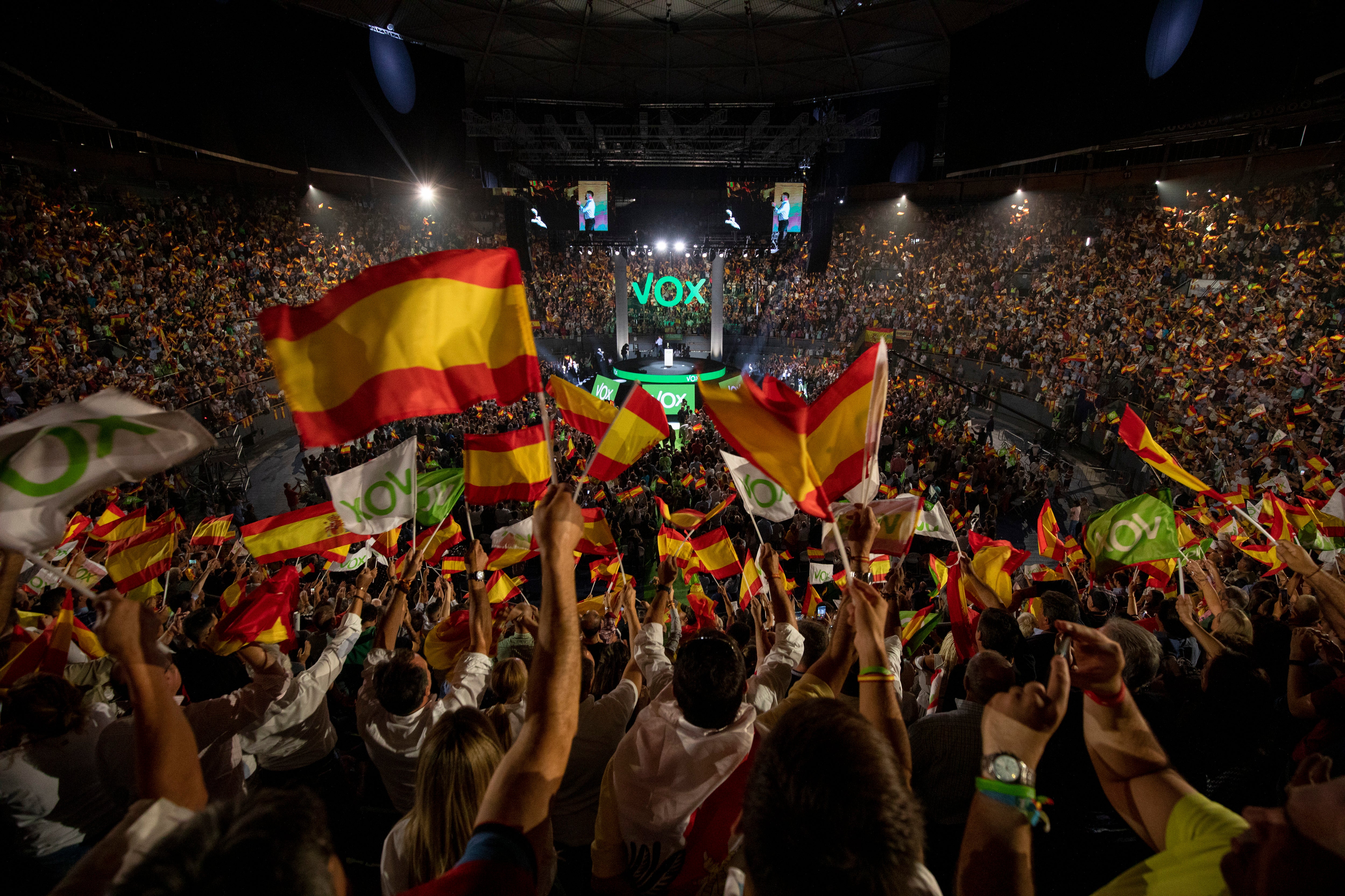 Supporters wave flags as the leader of far-right party Vox, Santiago Abascal, makes a speech in Madrid