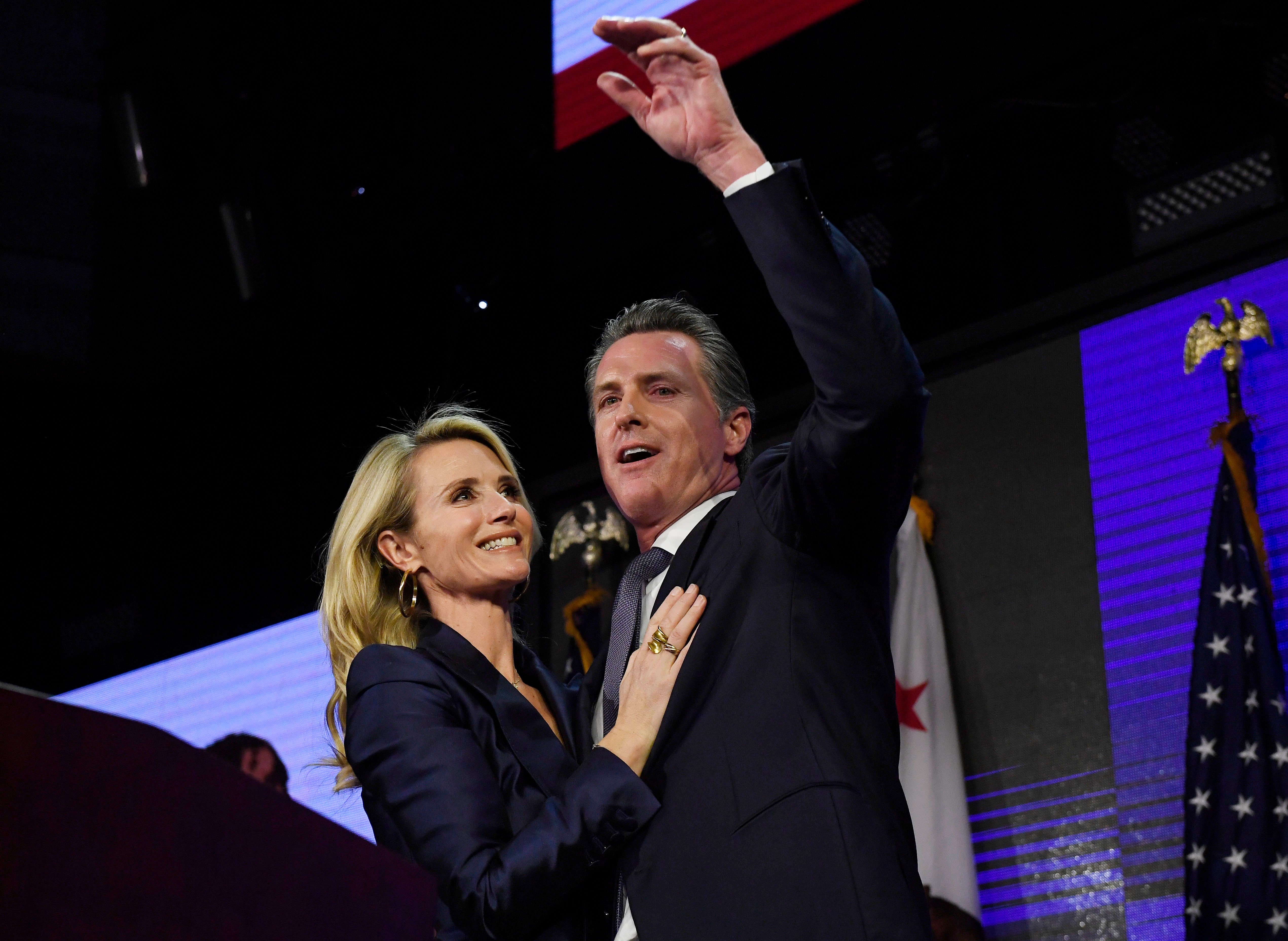 Gavin Newsom and his wife Jennifer Siebel Newsom wave to supporters during election night event on November 6, 2018 in Los Angeles, California