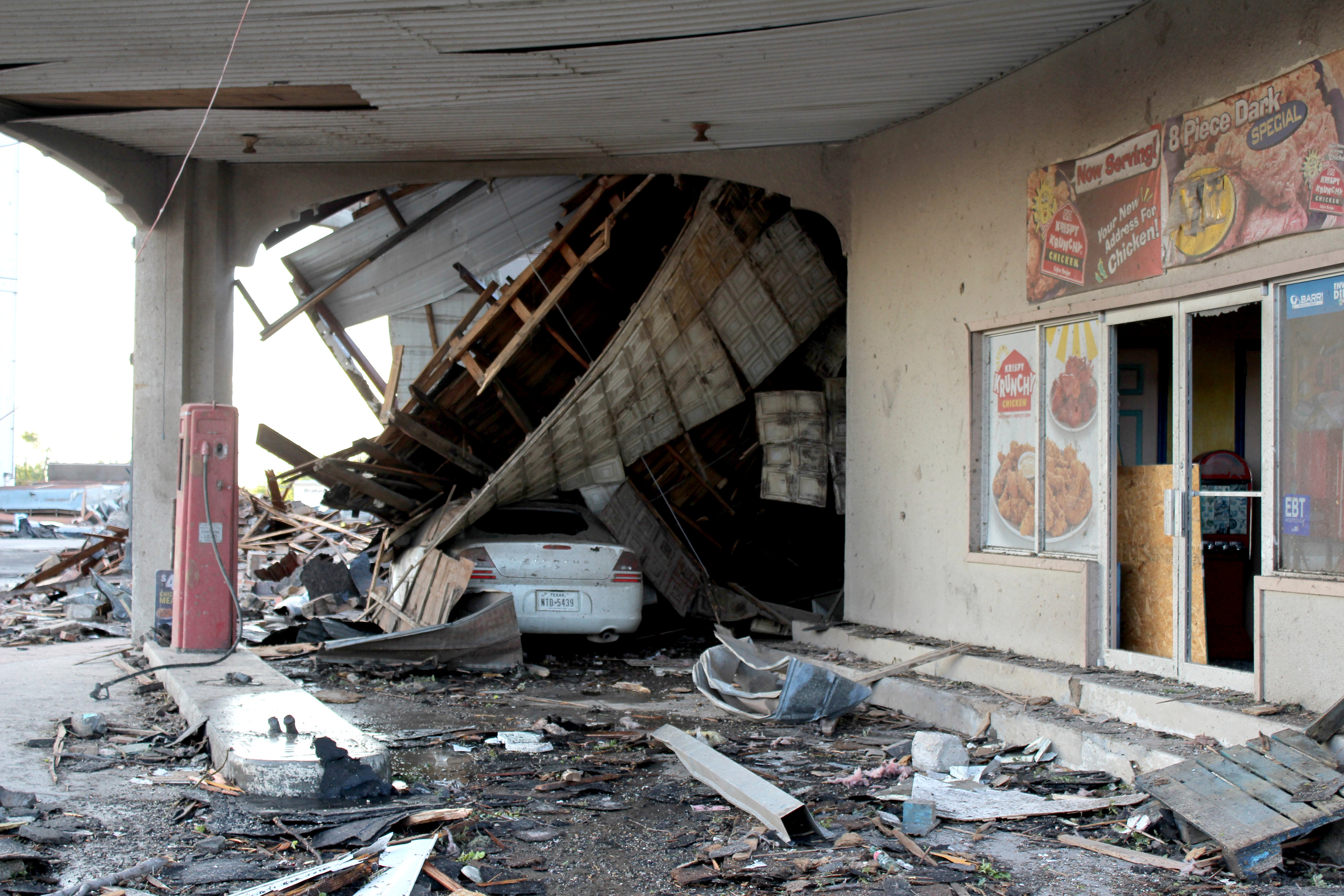 A vehicle sits by a destroyed business as cleanup efforts continue Friday, June 16, 2023, in Perryton, Texas