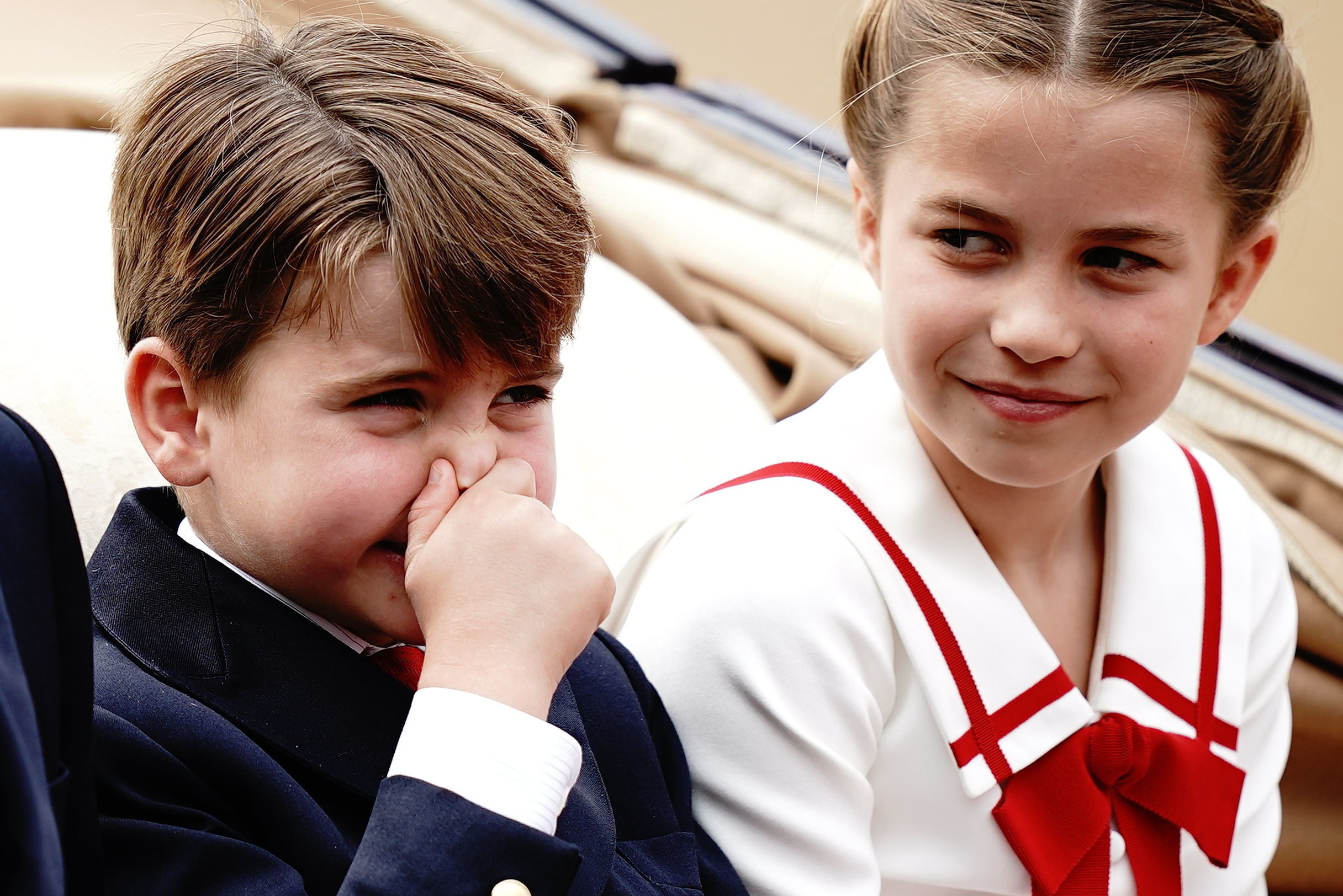 Big sister Charlotte looks on as Louis holds his nose