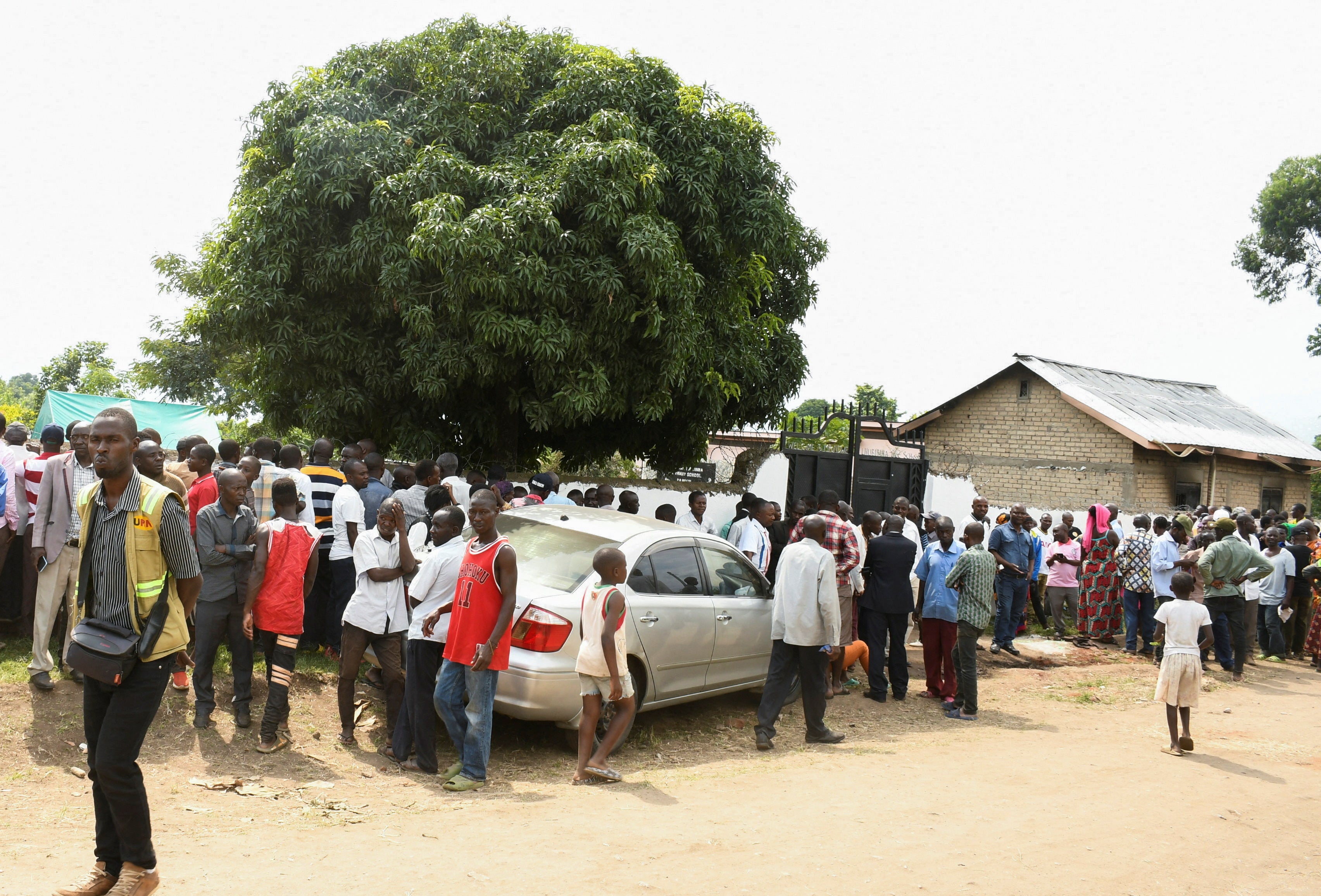 Families wait for news outside the school in Mpondwe