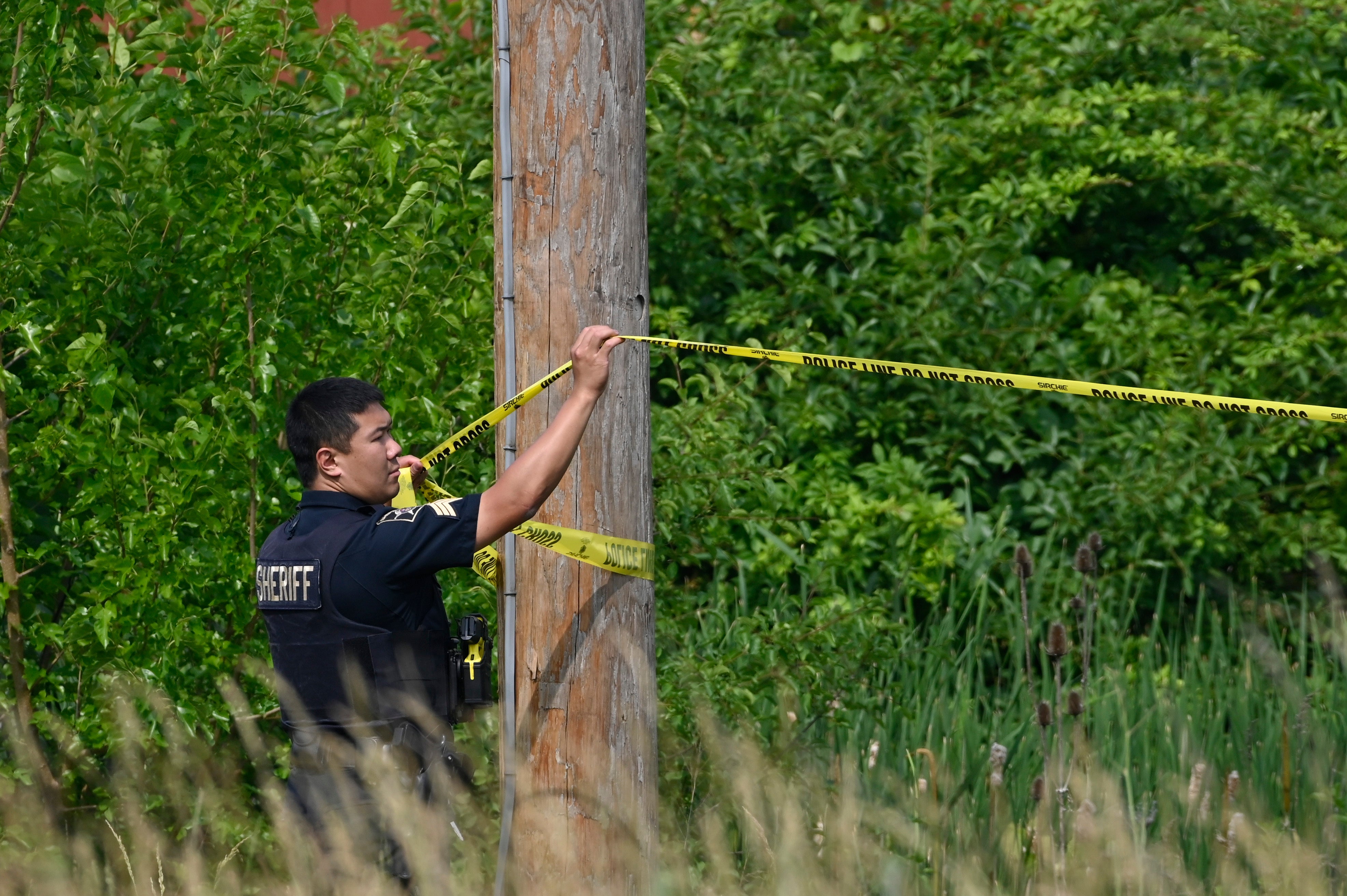 A police officer hangs caution tape at the scene of an overnight mass shooting at a strip mall in Willowbrook