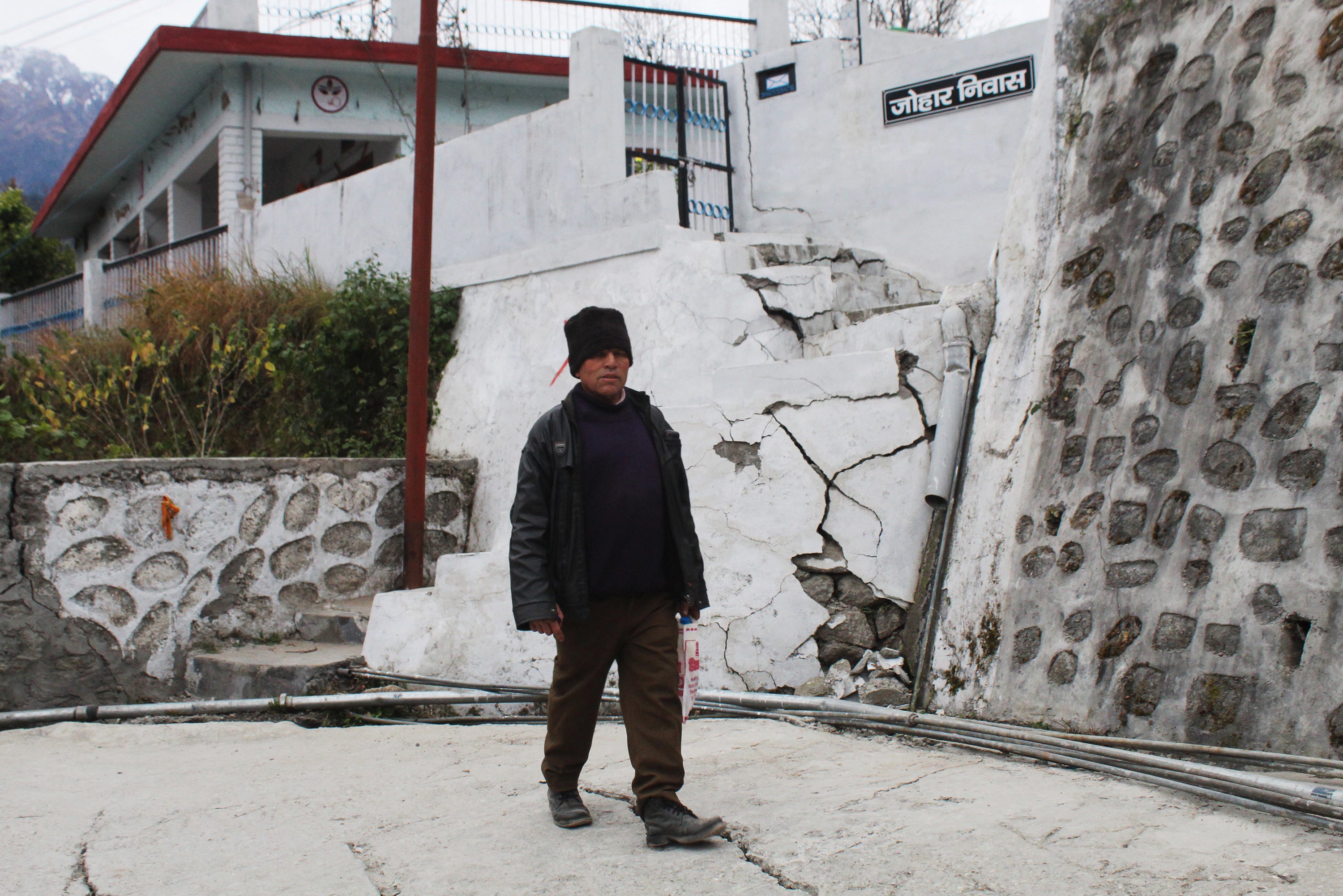 A resident walks past a house damaged with cracks in Joshimath, in Uttarakhand state’s Chamoli district