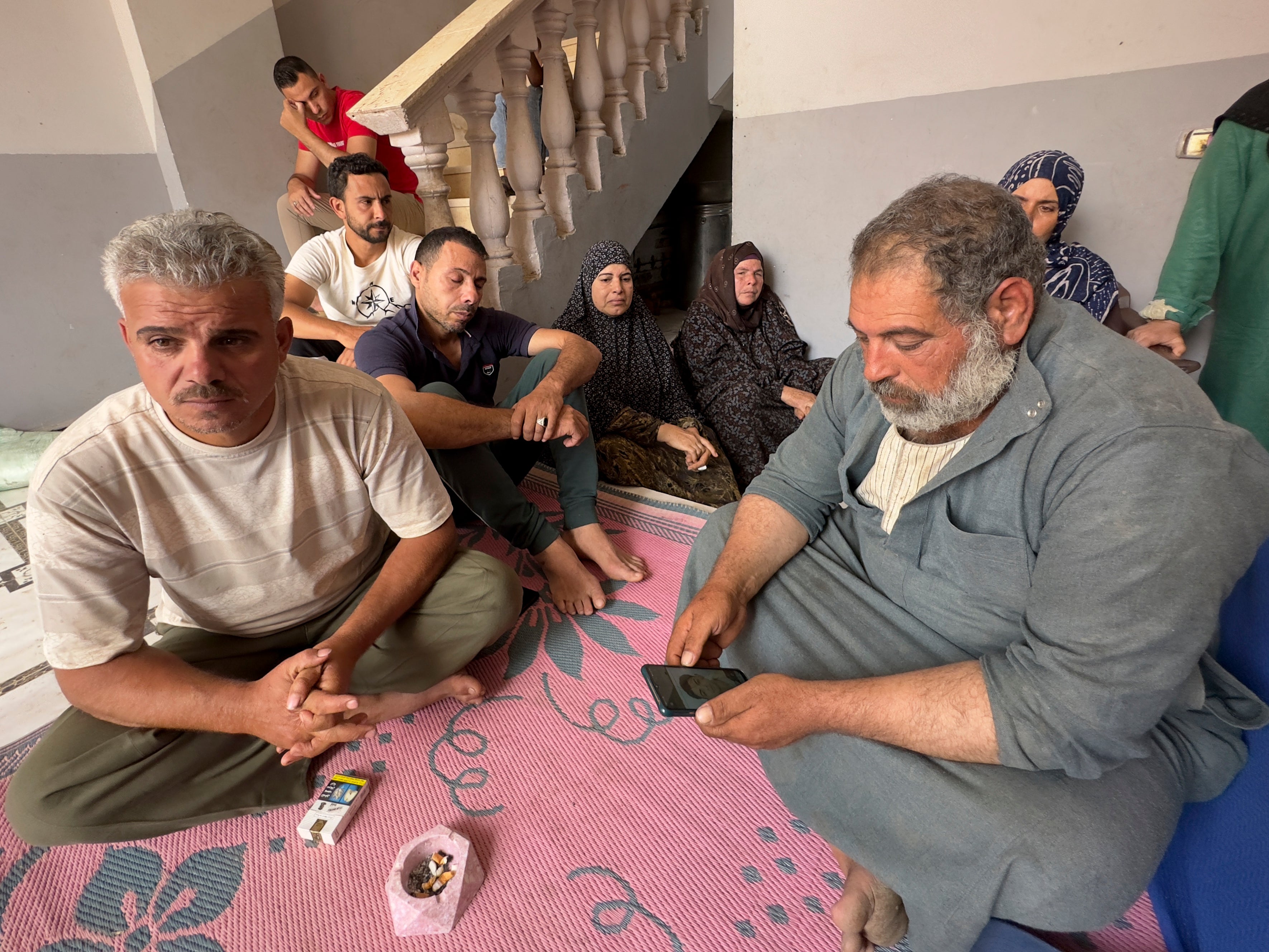 Mohammed Saleh, father of 18-year-old Yahia Saleh, holds a phone with a photo of his son, who is one of dozens from the village feared to have drowned