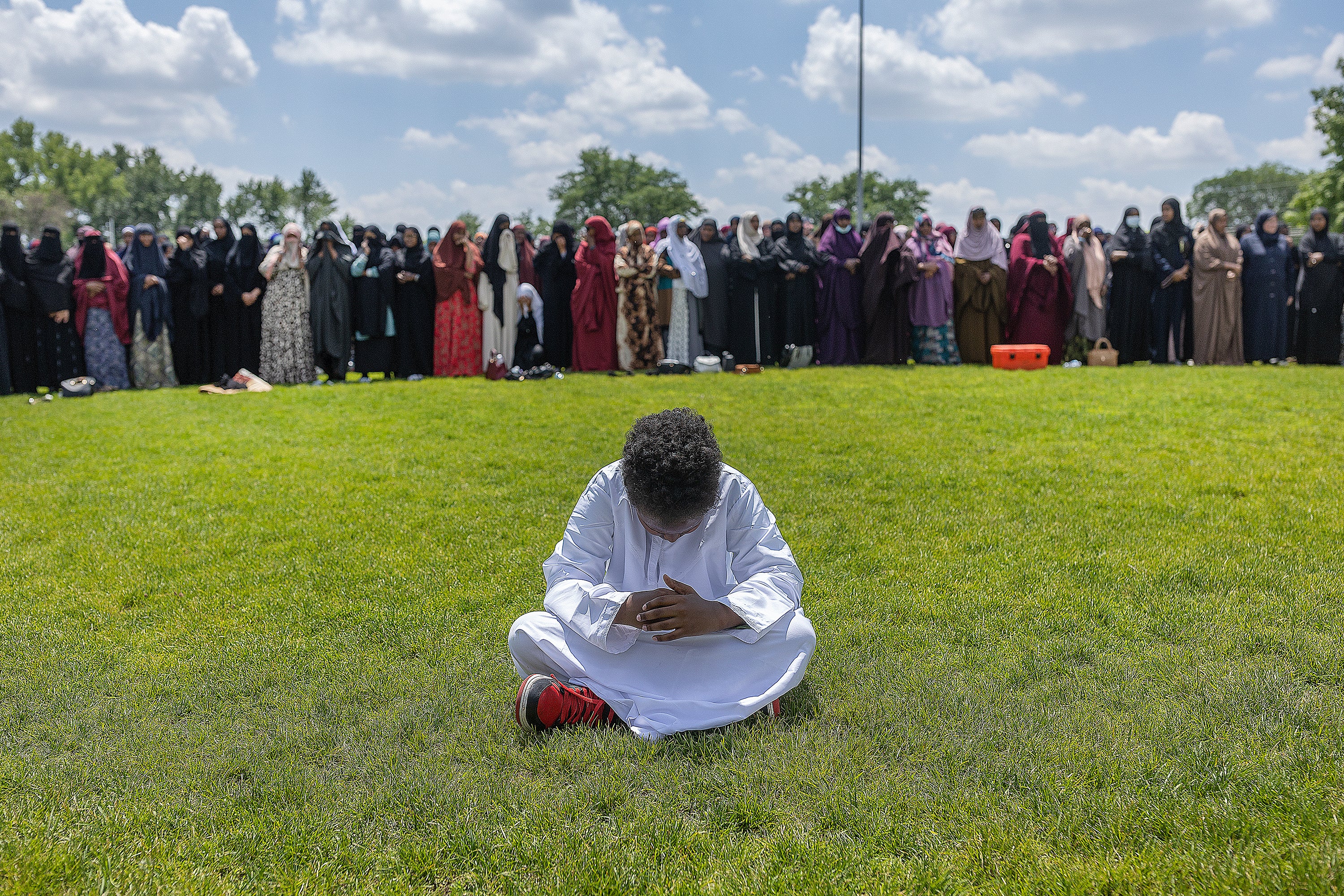 A young boy prays as women line up in prayer during the funeral for the people women killed in a car crash on Lake Street, at the Dar Al-Farooq Islamic Center in Bloomington, Minn., on Monday, June 19, 2023.