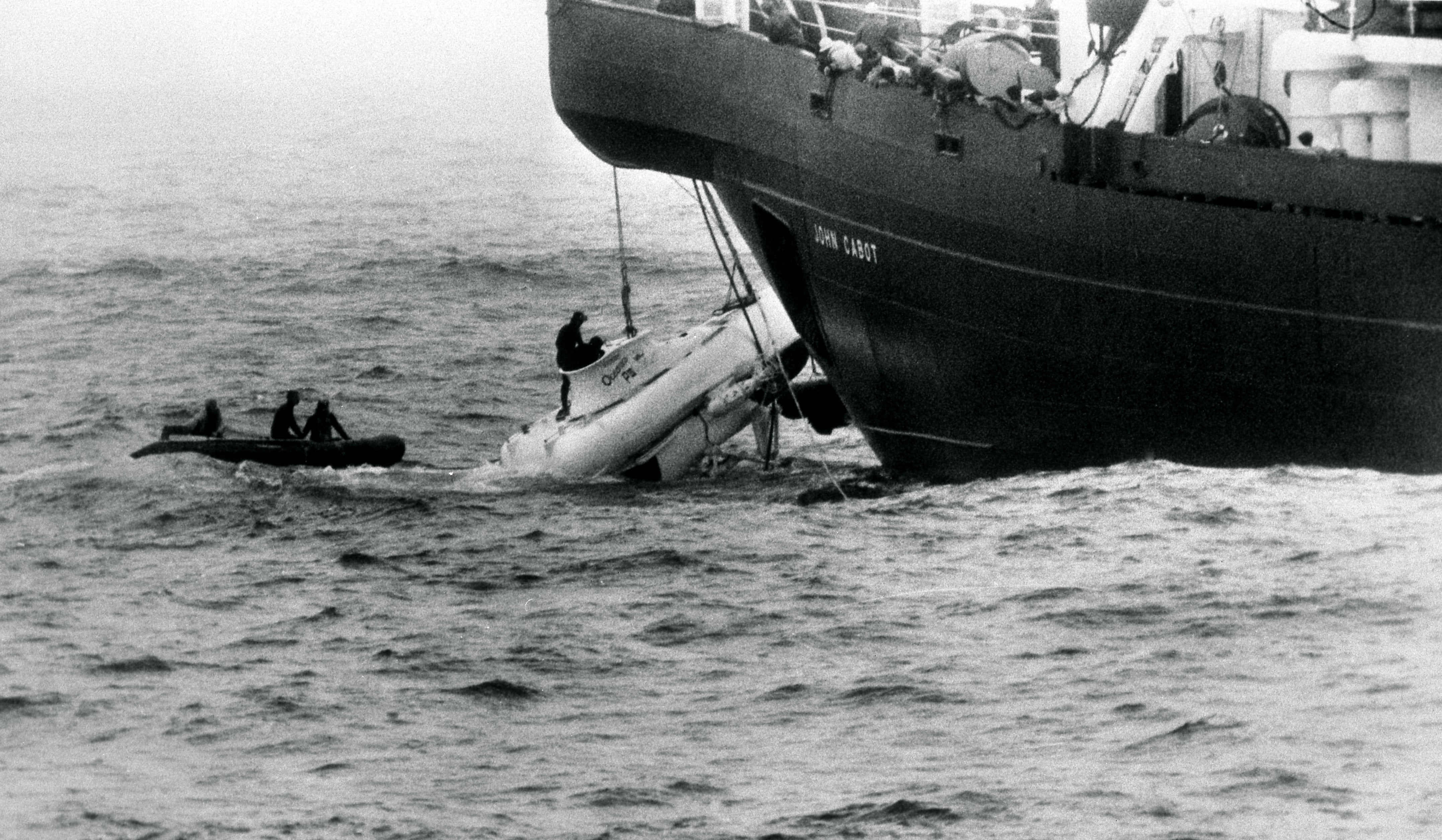 Divers begin to open the hatch of the minature submarine Pisces III as she breaks water under the John Cabot after being hauled from the Atlantic seabed off Cork