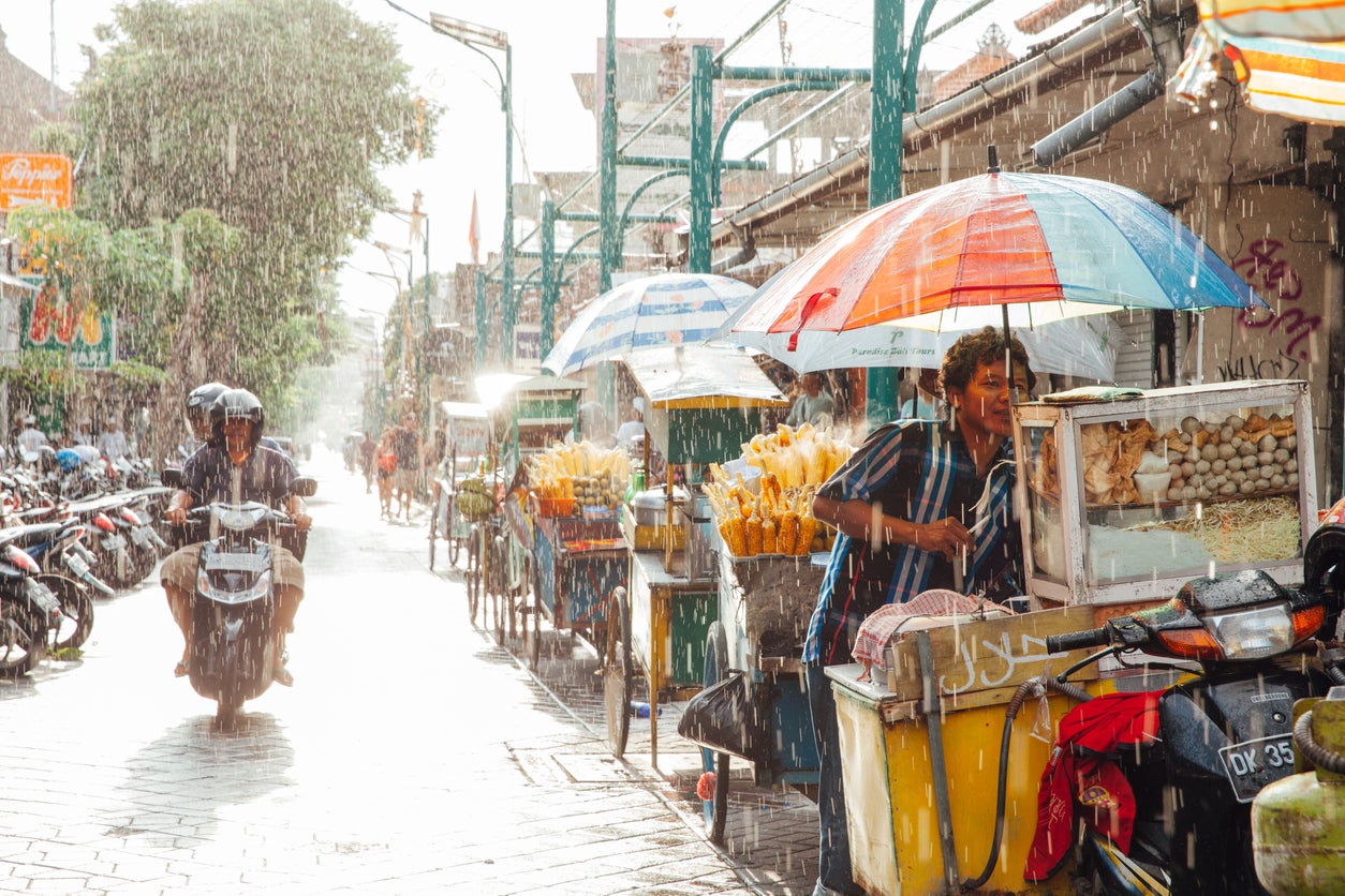 Street vendors in Kuta shelter from a downpour