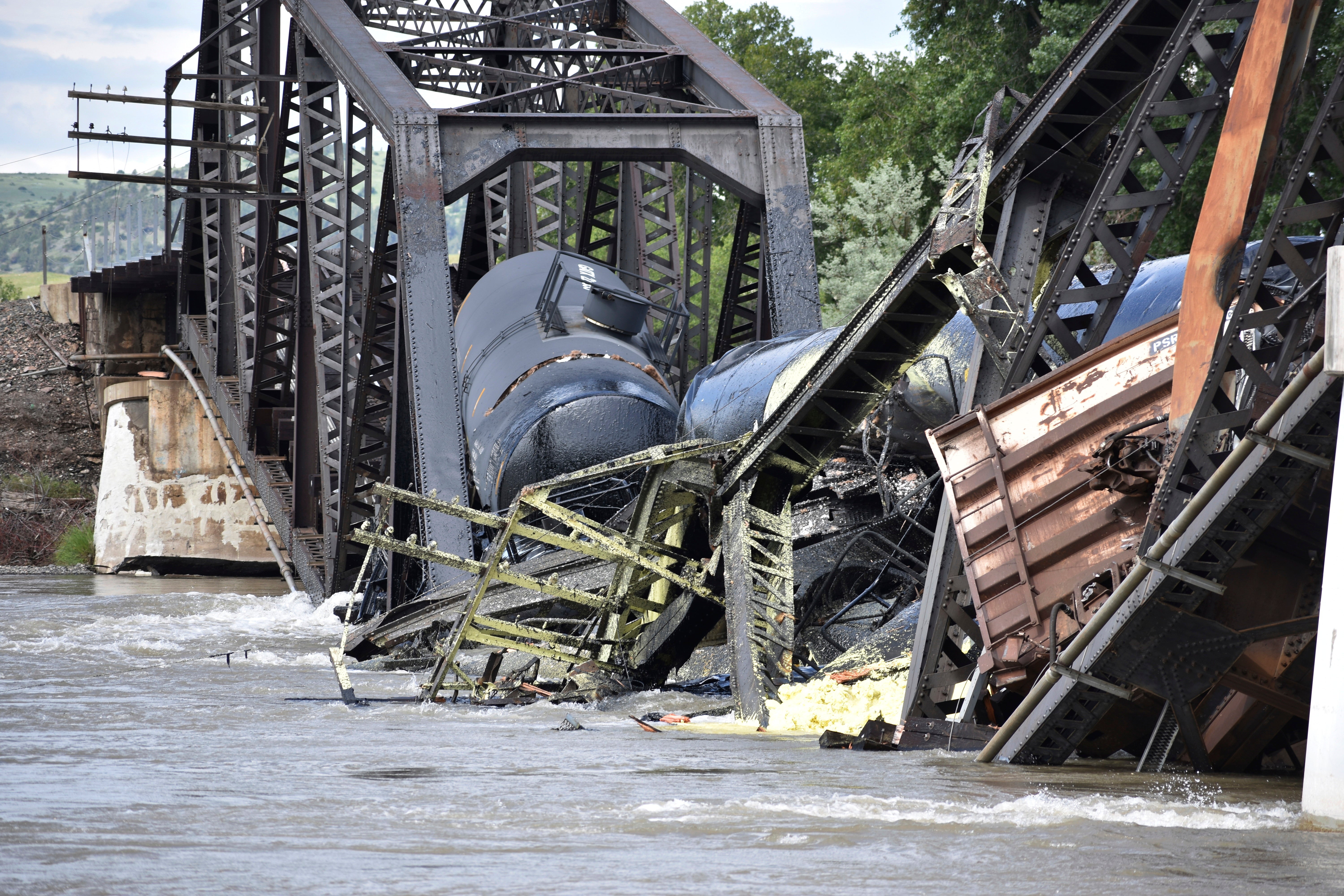 Several train cars are immersed in the Yellowstone River after a bridge collapse near Columbus, Mont., on Saturday, June 24, 2023