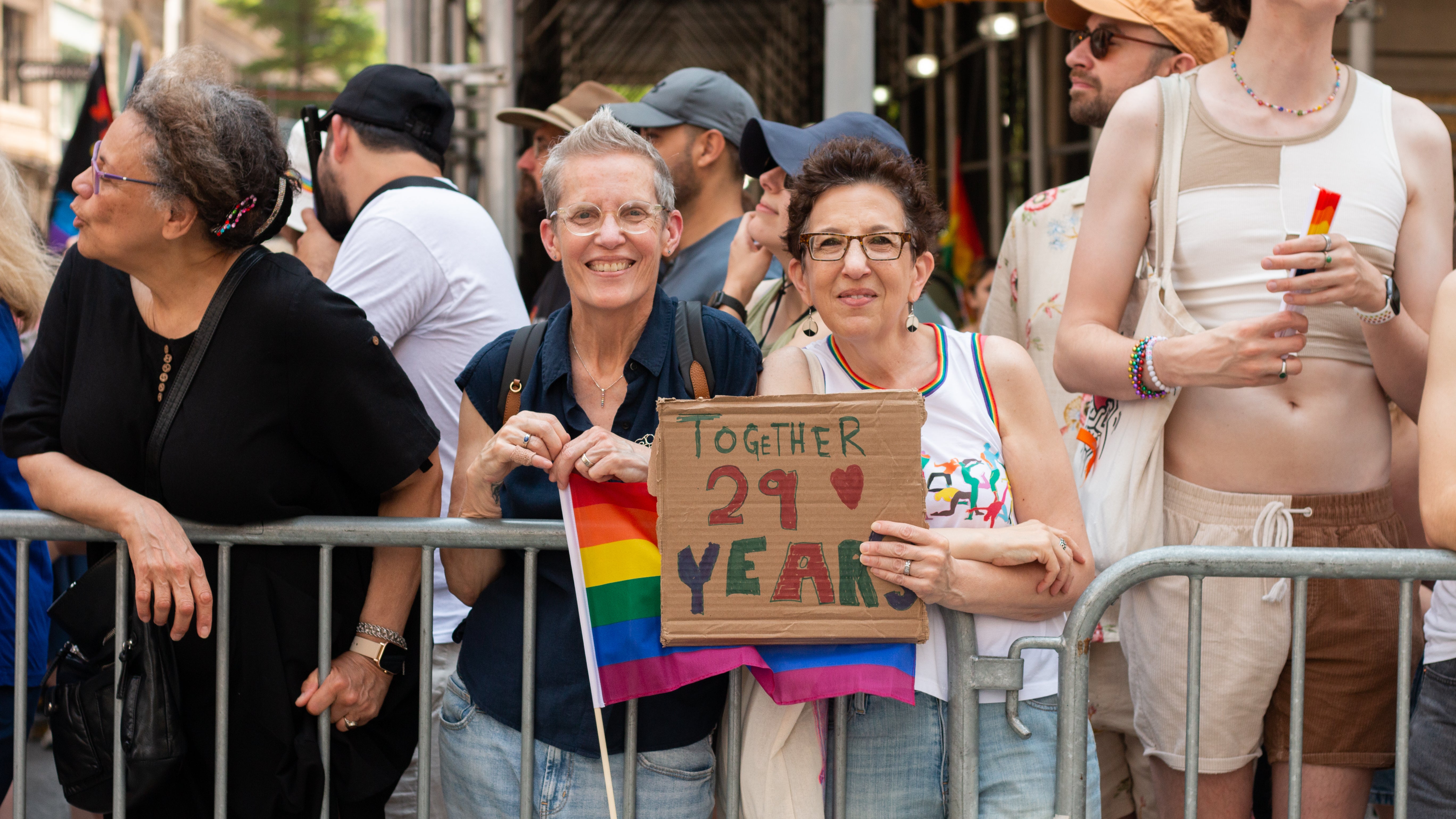 A queer couple holds up a sign that says, “together 29 years” at New York City Pride